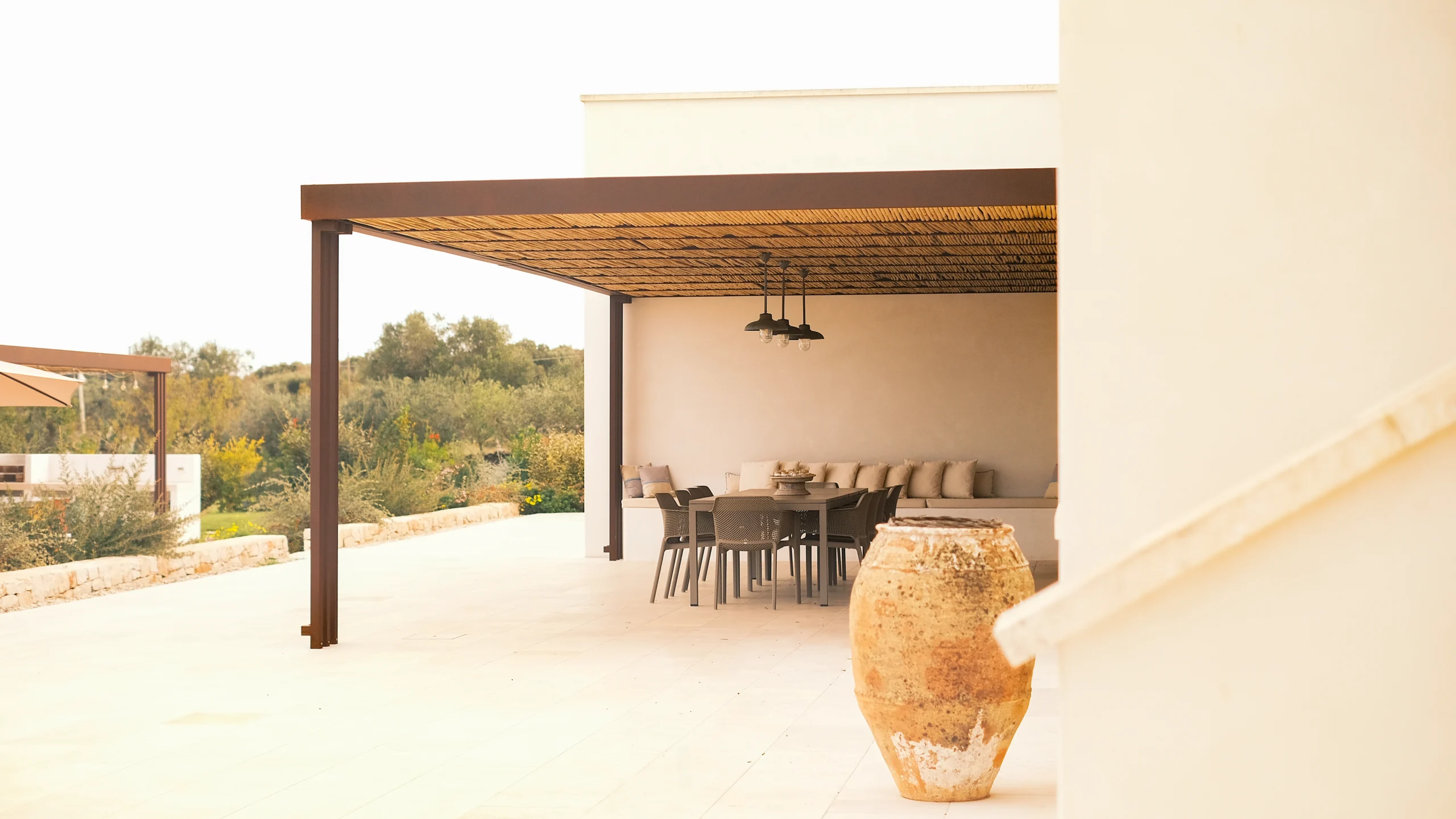 Covered outdoor dining table with pendant lights in a luxury villa in southern Italy