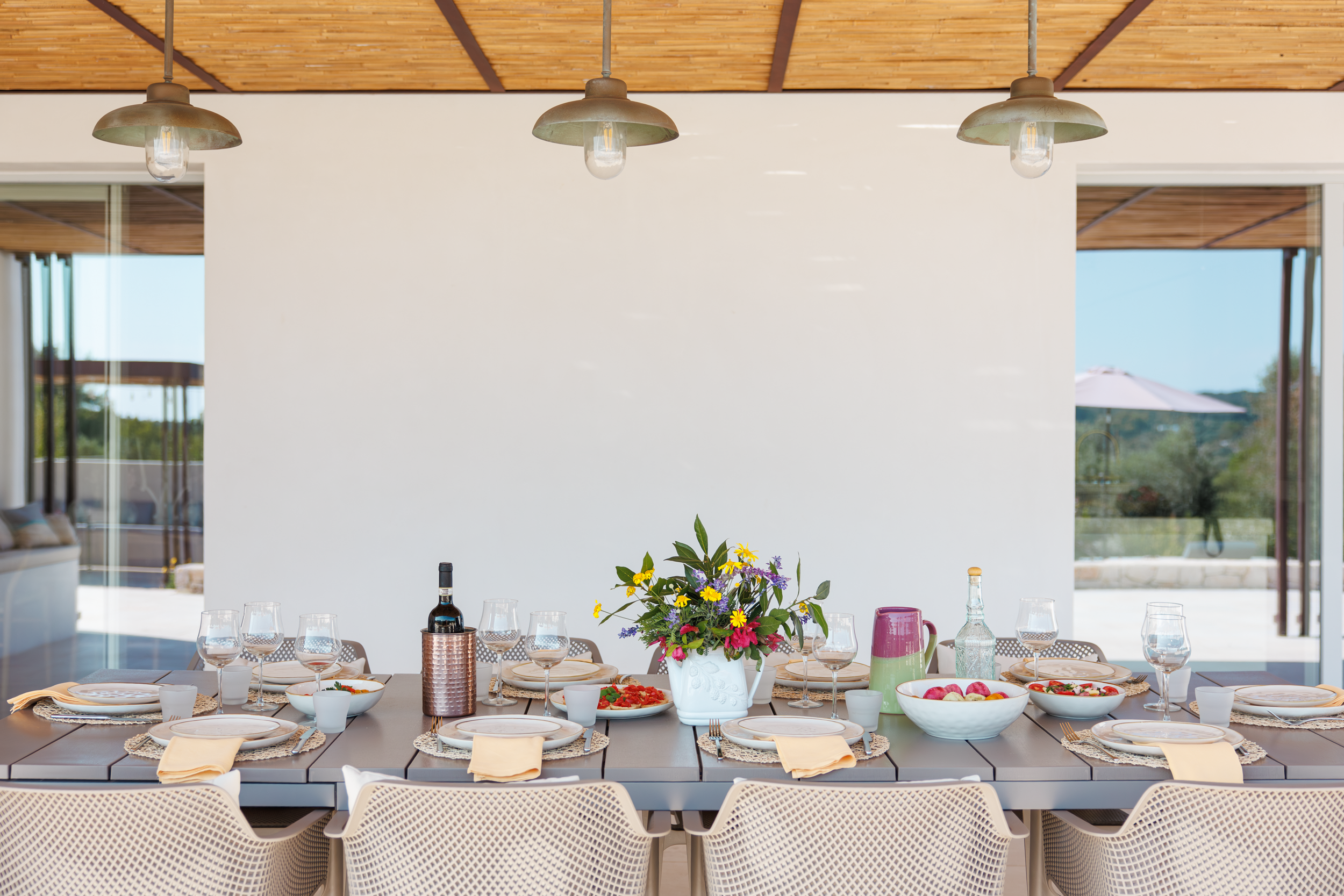 Covered outdoor dining area with large table and chair seating in a luxury villa in Puglia
