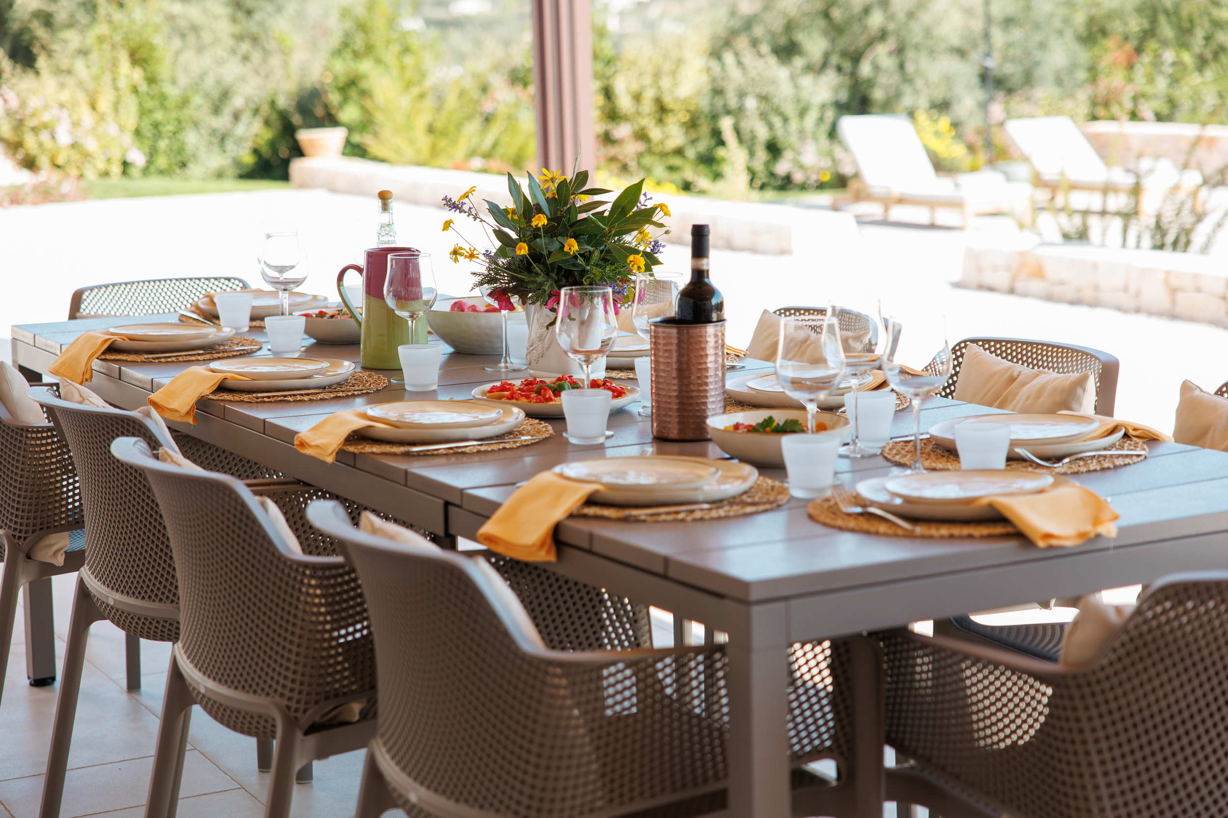Outdoor dining table set for guests with garden and pool view in a Puglia villa