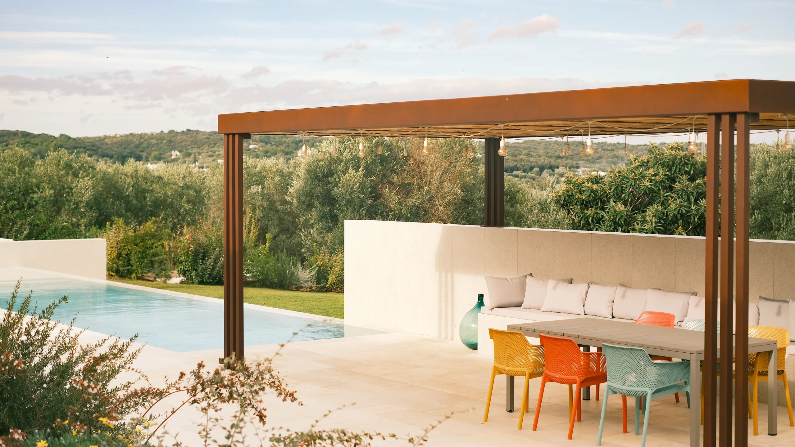 Outdoor dining table set under a pergola with designer lighting in a luxury villa in Puglia