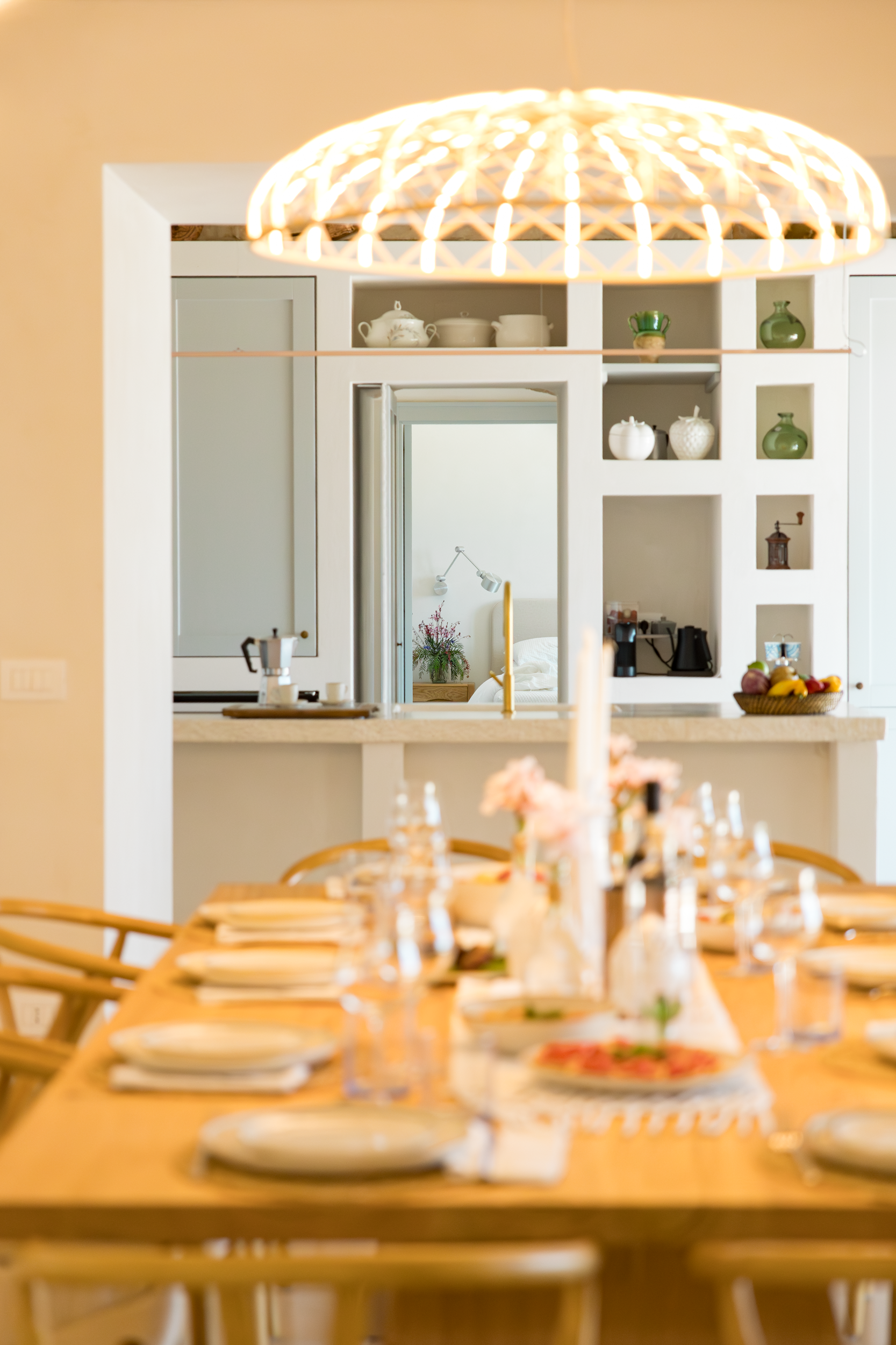 Indoor dining room with wooden table, set for guests, and open kitchen in a luxury villa in Puglia