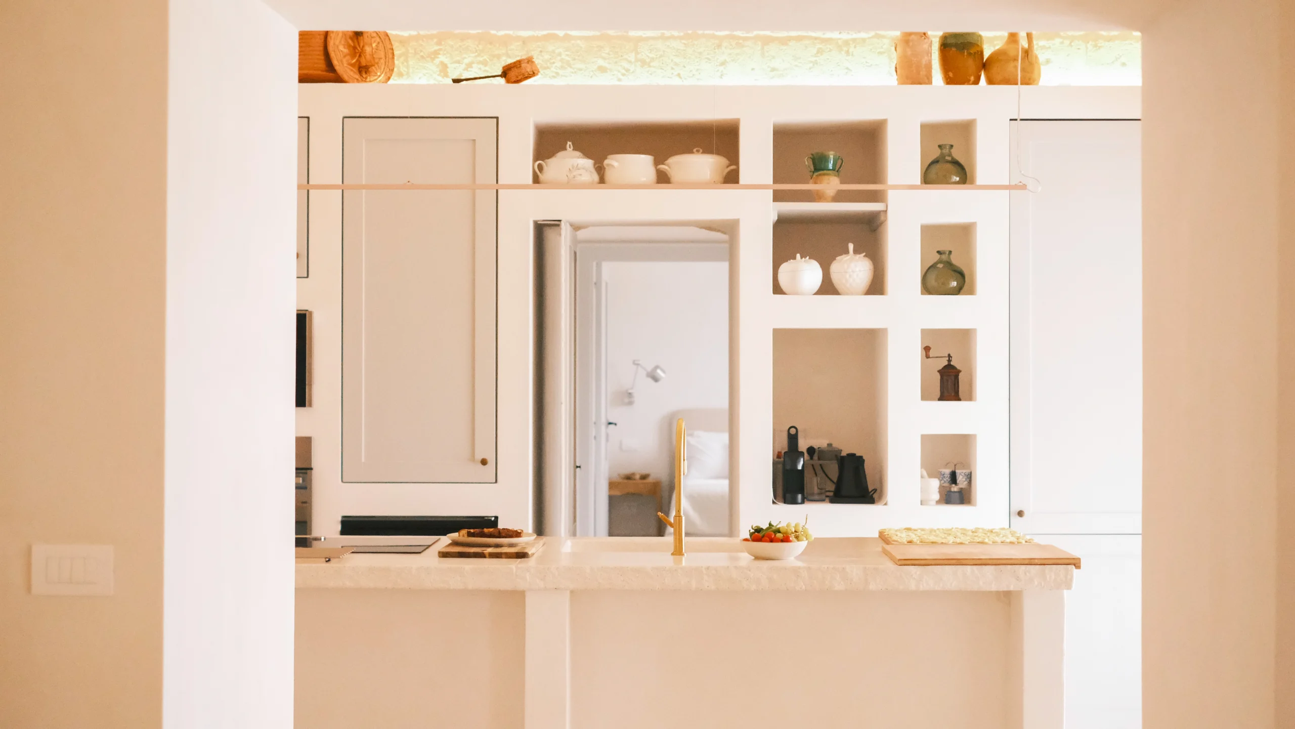 Minimalist trullo kitchen interior with bespoke shelves, ceramic details and soft natural light in Puglia