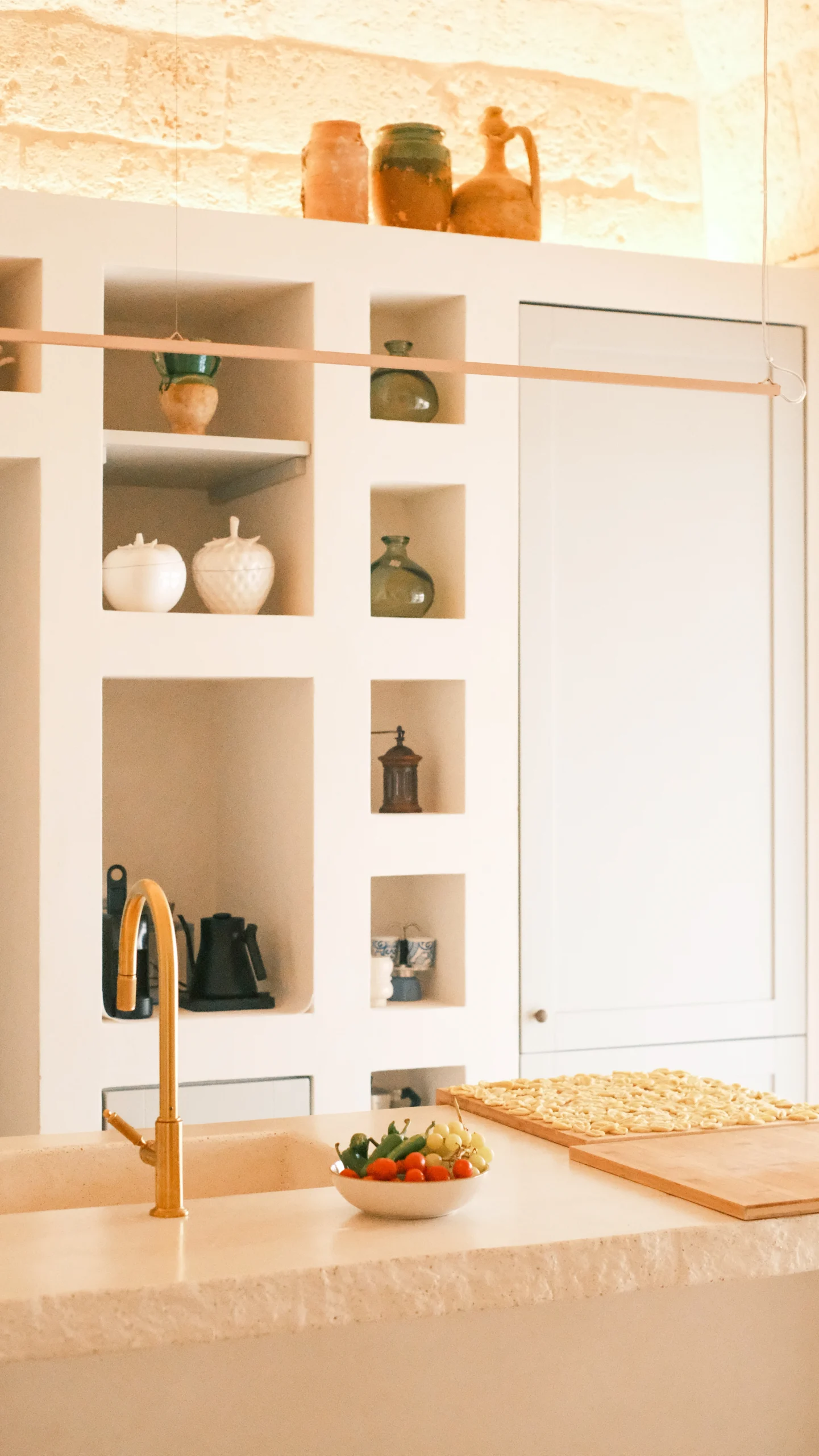 Luxury kitchen island with brass faucet, stone worktop and artisanal ceramics in a Puglia trullo