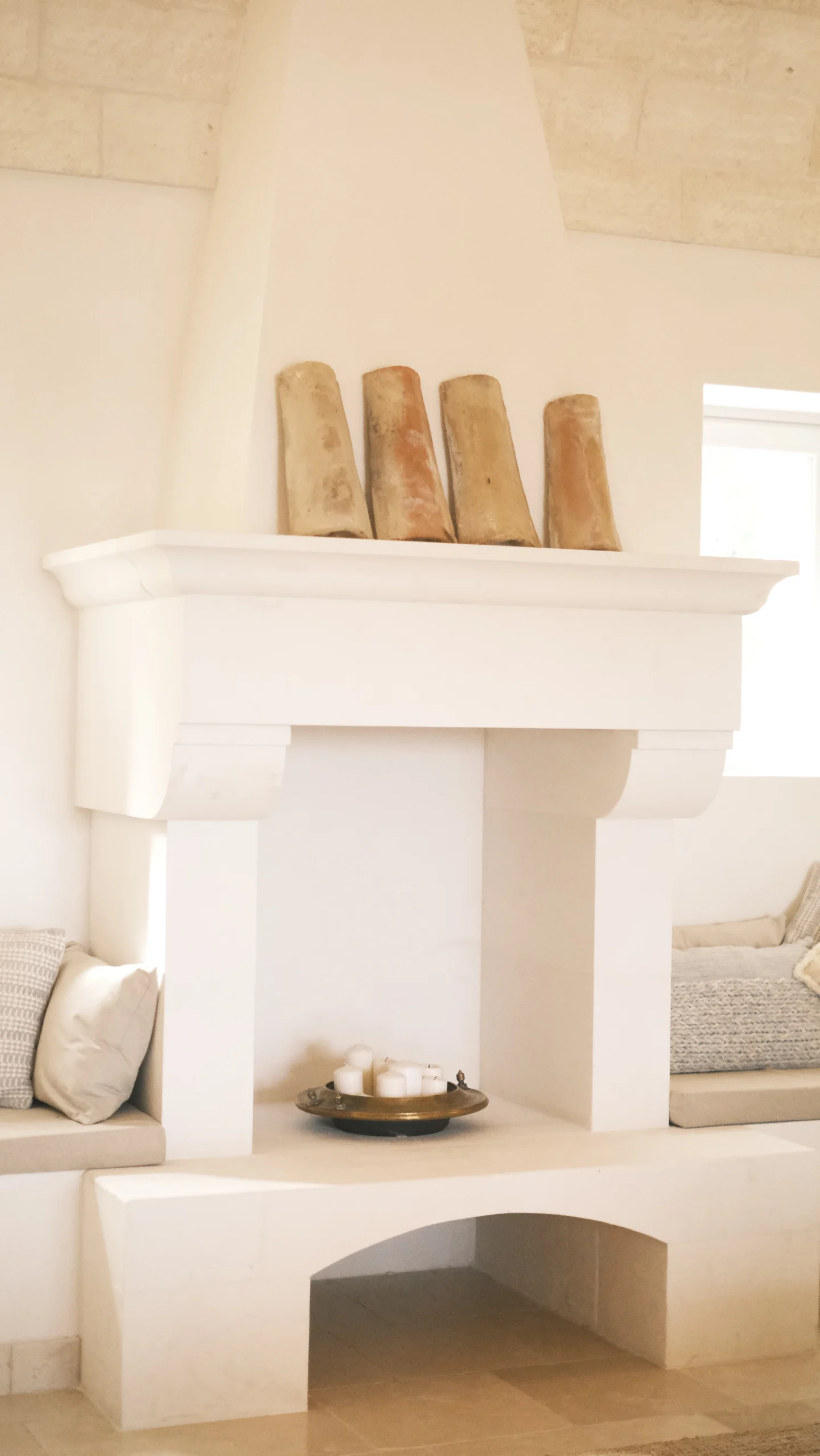 Elegant living room with stone fireplace, built-in seating and vaulted ceiling in a luxury trullo villa