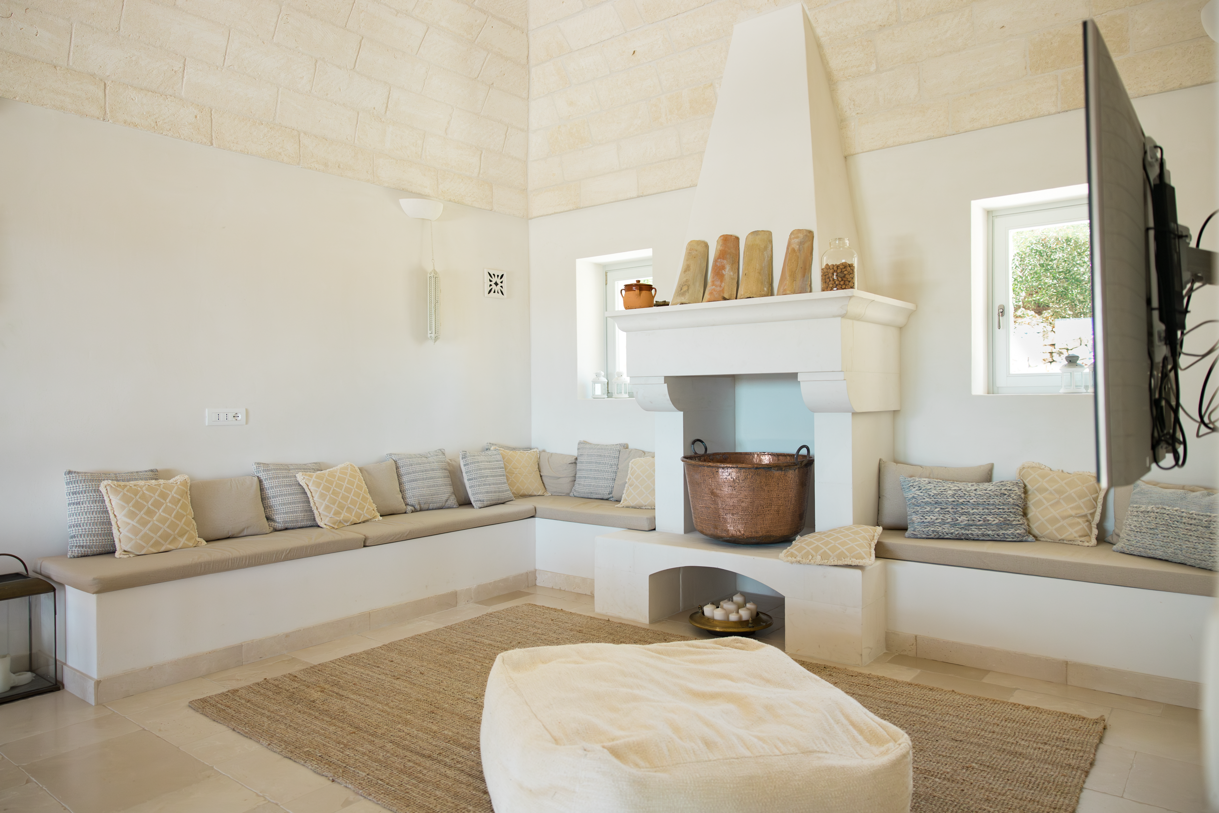 Bright living room with vaulted stone ceiling, fireplace and integrated seating in a luxury villa in Puglia
