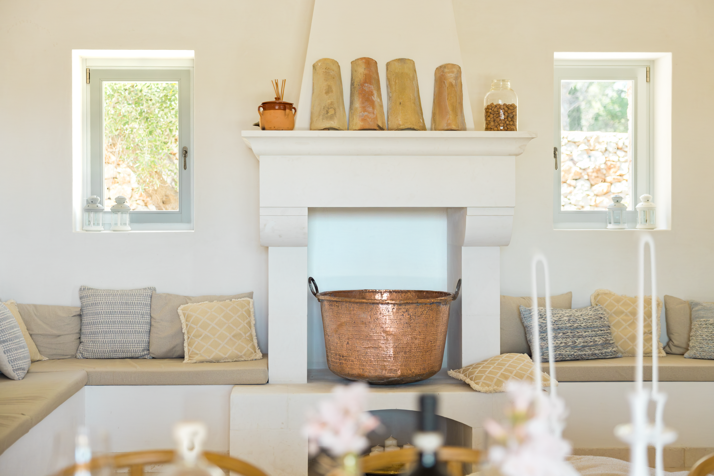 Elegant living area with fireplace, copper basin and built-in seating in a high-end villa in Puglia