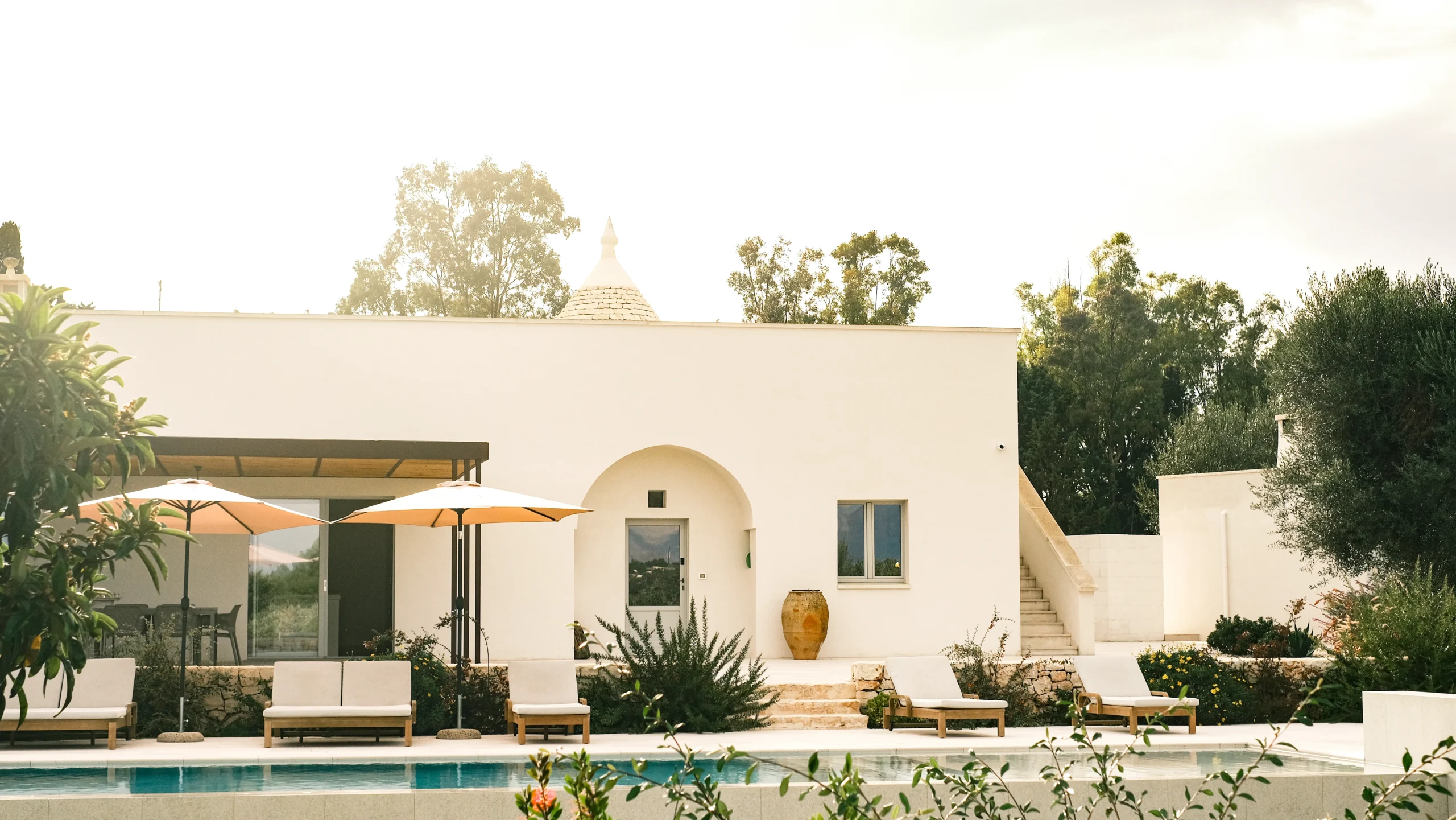 Front view of a luxury villa with pool, sun loungers and pergola in the Puglian countryside
