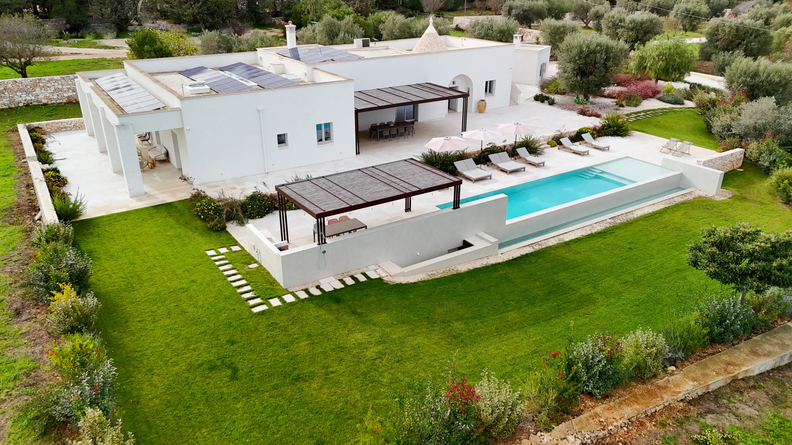 Aerial view of a modern luxury villa with infinity pool and olive trees in Puglia