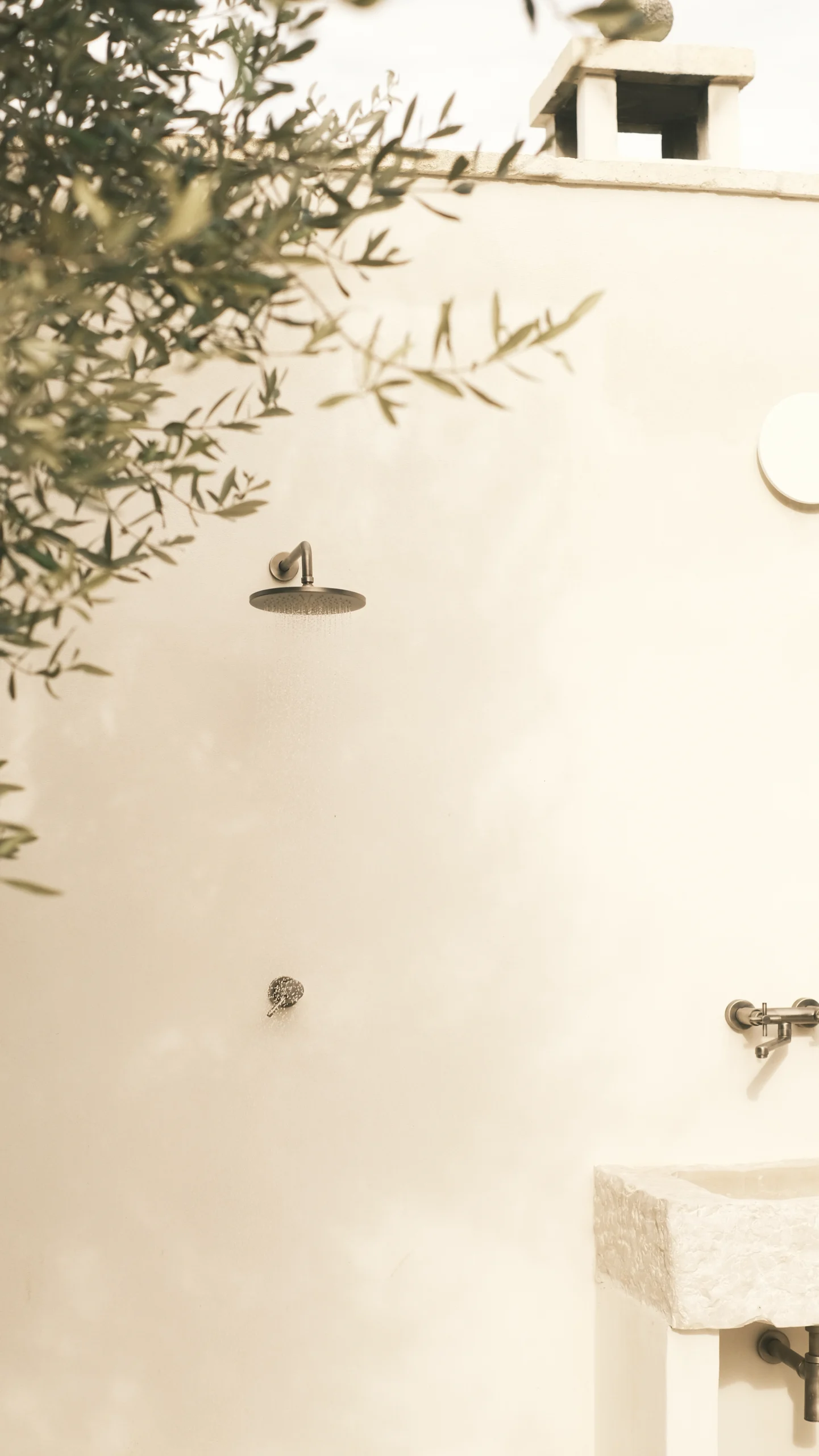Minimalist outdoor shower set among olive trees in a luxury villa in Puglia