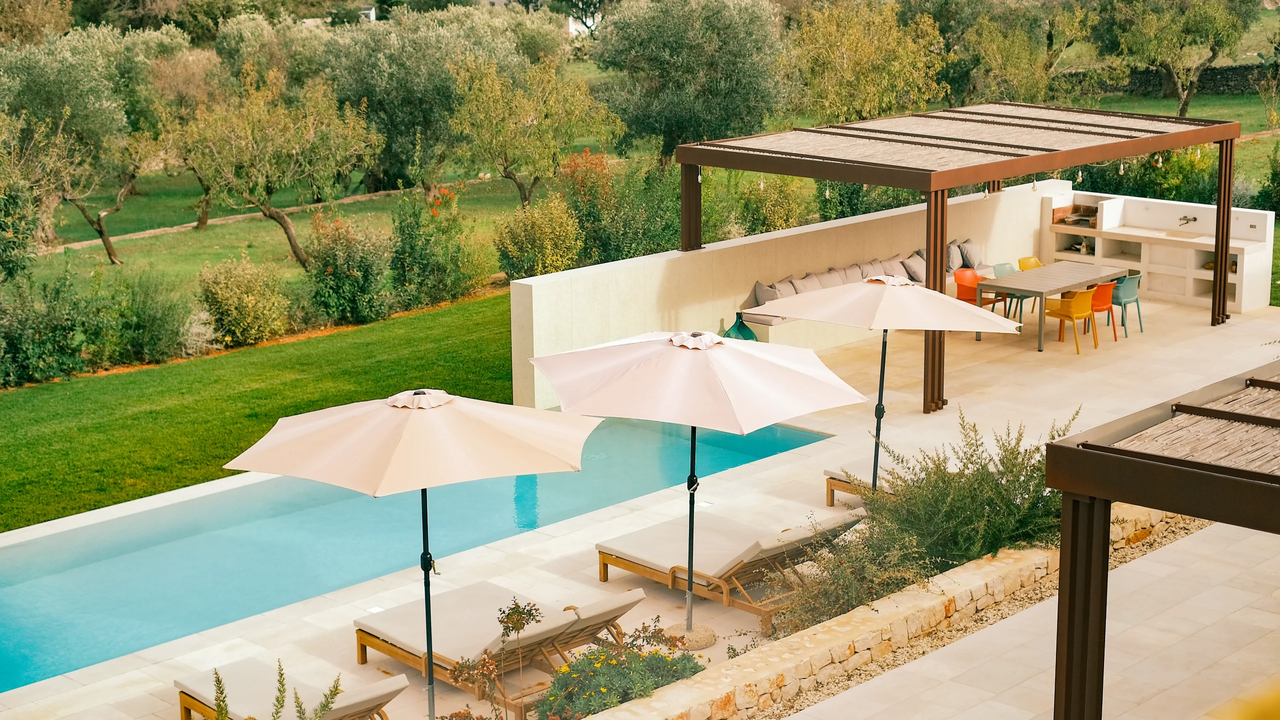 Long infinity swimming pool with sun loungers and olive grove views in Puglia