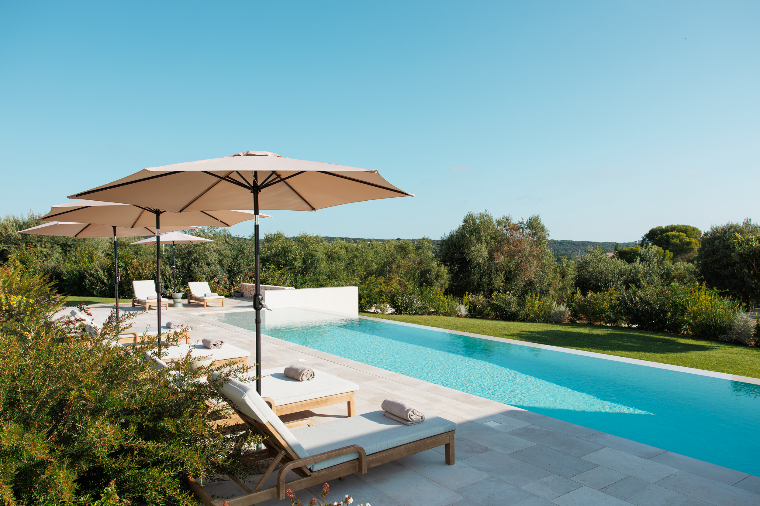 Luxury swimming pool with sun loungers overlooking olive groves in a private villa in Puglia