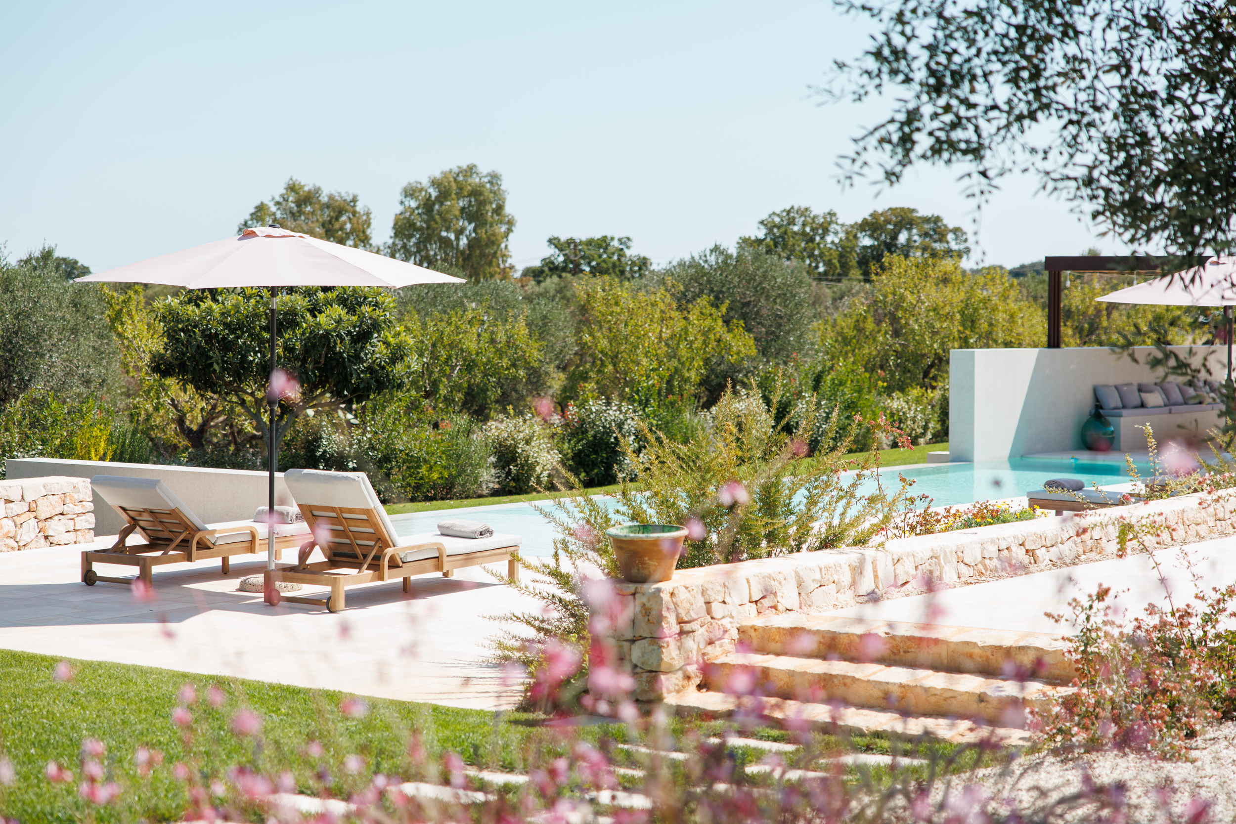 Elegant poolside area with parasols and loungers in a contemporary villa in Puglia, Italy