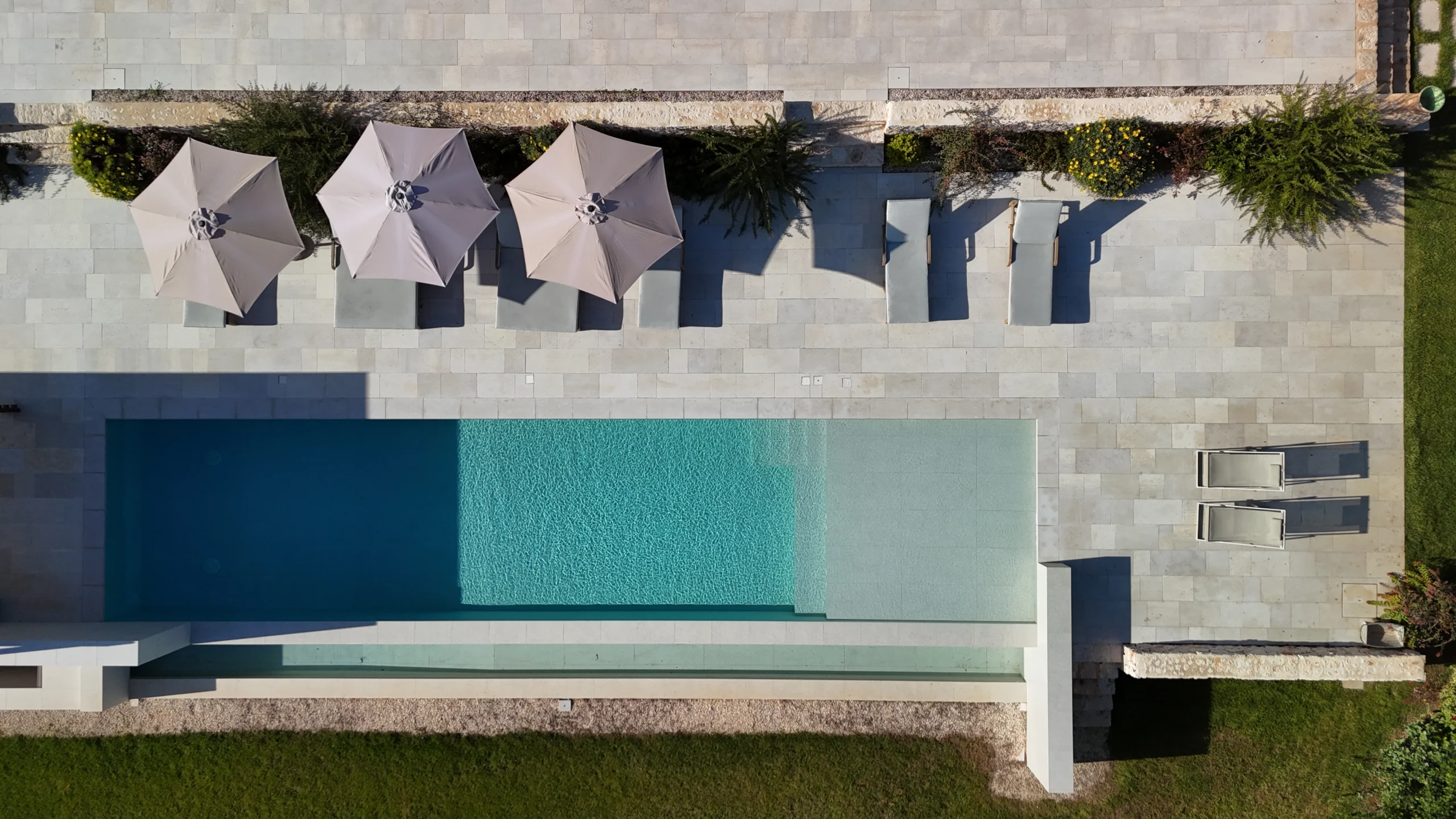 Aerial view of a private infinity pool with sun loungers and parasols in a luxury villa in Puglia, Italy