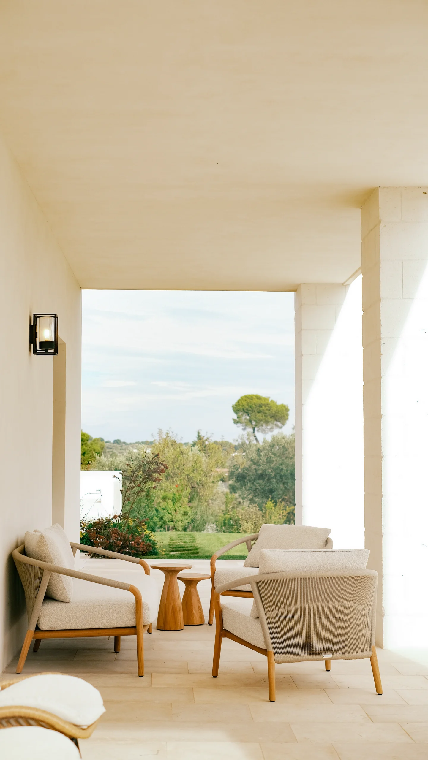 Covered terrace with outdoor lounge furniture overlooking the Puglian countryside at a luxury villa