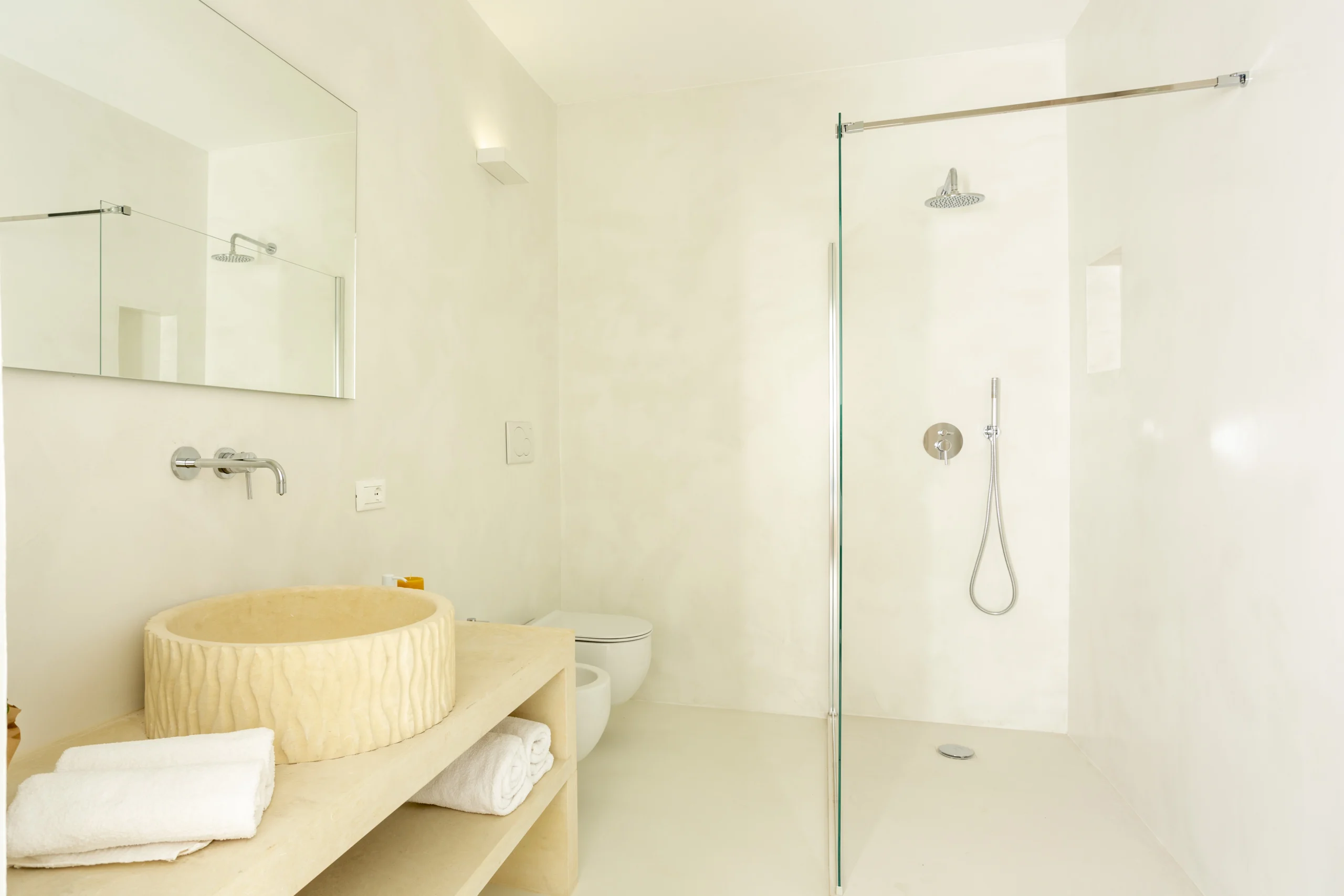 Villa Leucade modern bathroom with walk-in shower, stone basin and minimalist design in luxury villa in Puglia.