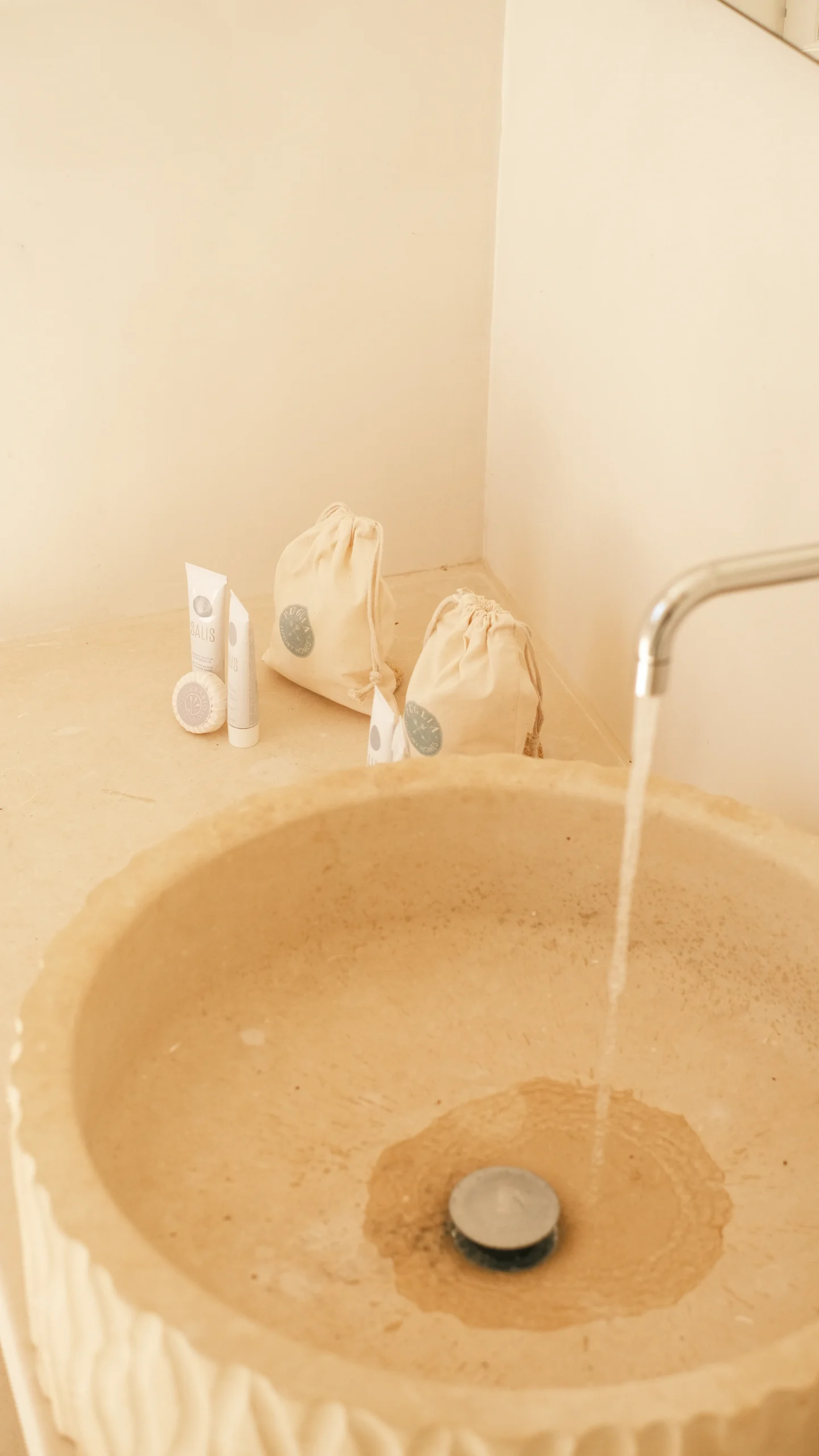 Villa Leucade sculpted stone sink with running water, luxury bathroom detail in a Mediterranean villa in Puglia.