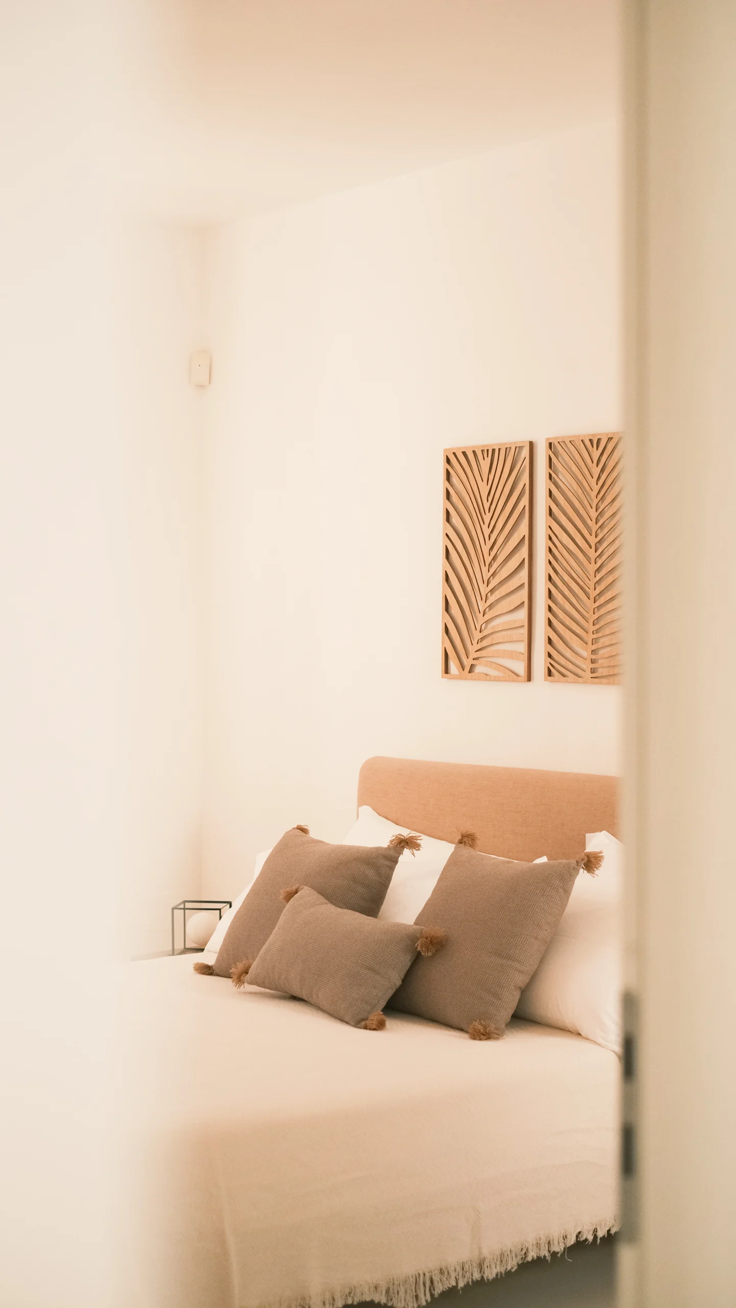 Cozy designer bedroom with neutral tones, textured cushions and natural wood decor