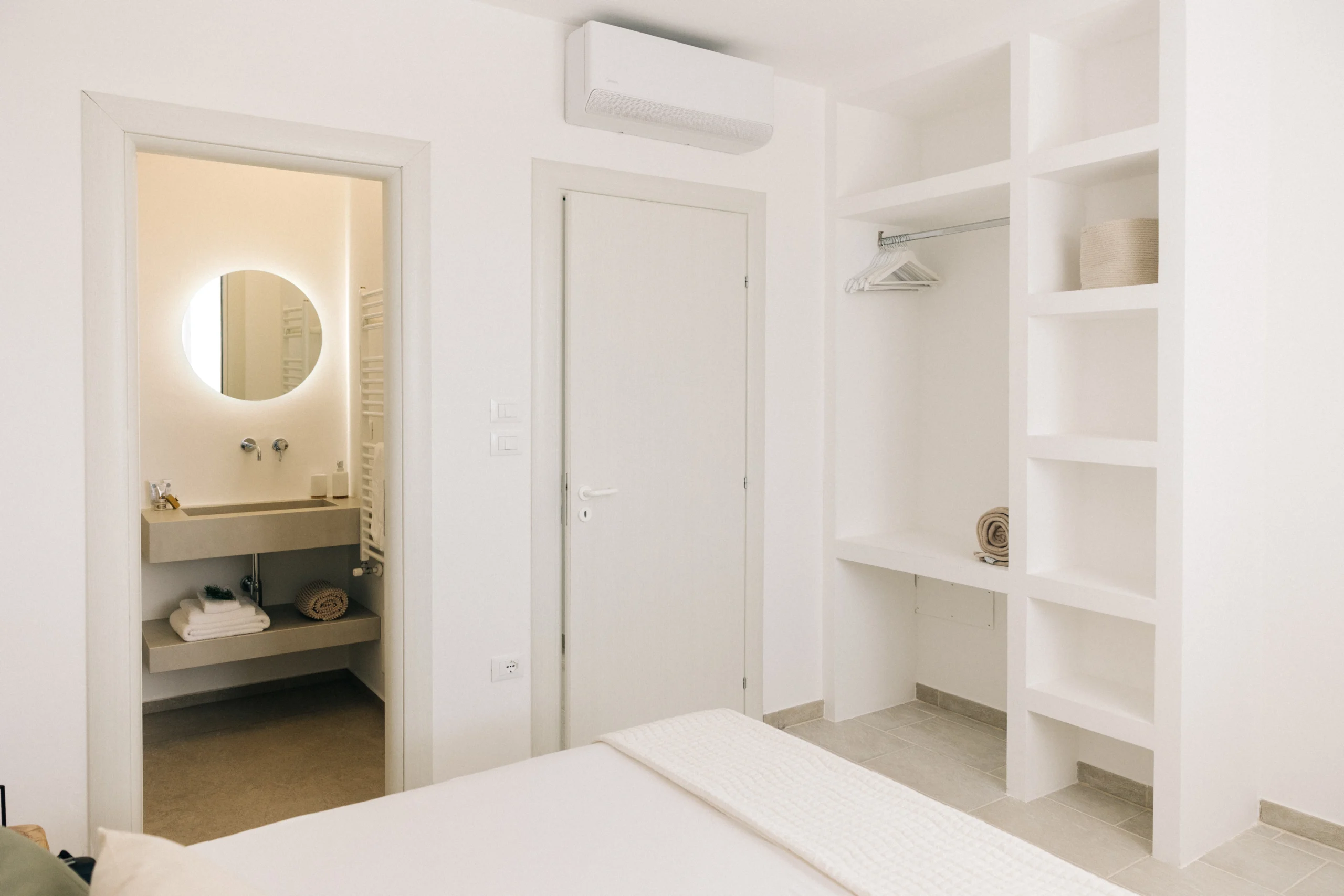 Luxury bedroom at Villa Leucade with minimalist design, open bathroom view and built-in wardrobe in modern Puglia villa.