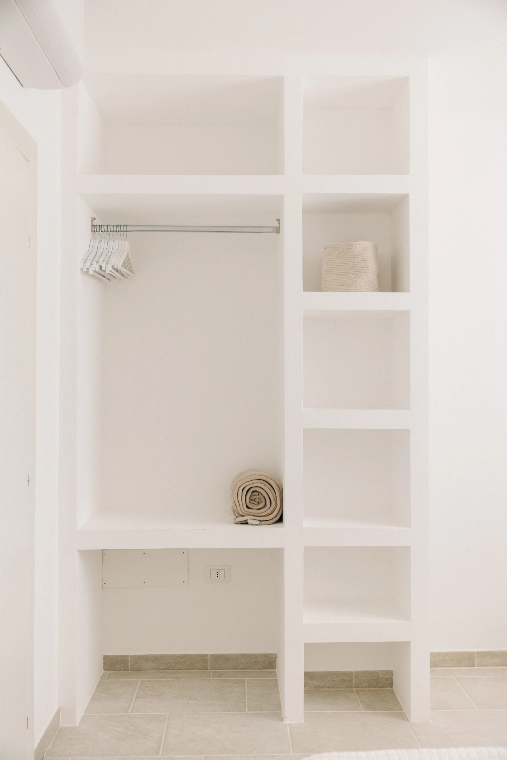 Built-in open wardrobe with shelves and hangers in modern Puglia villa bedroom