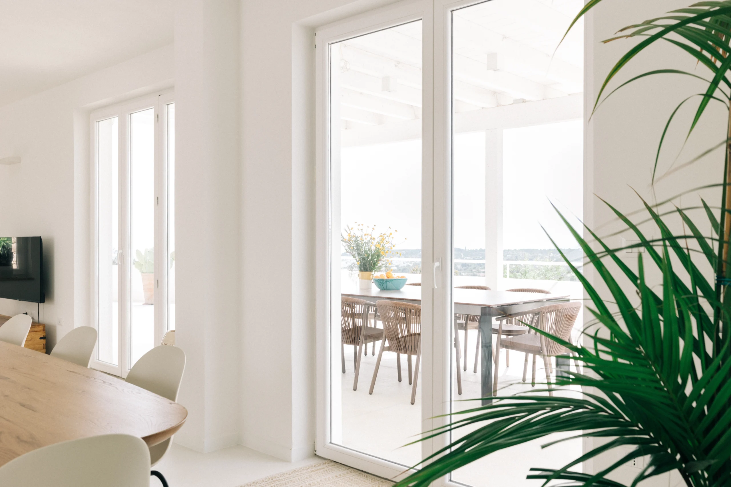 Luxury outdoor dining space at Villa Leucade with modern table, wicker chairs and pool view in Puglia.