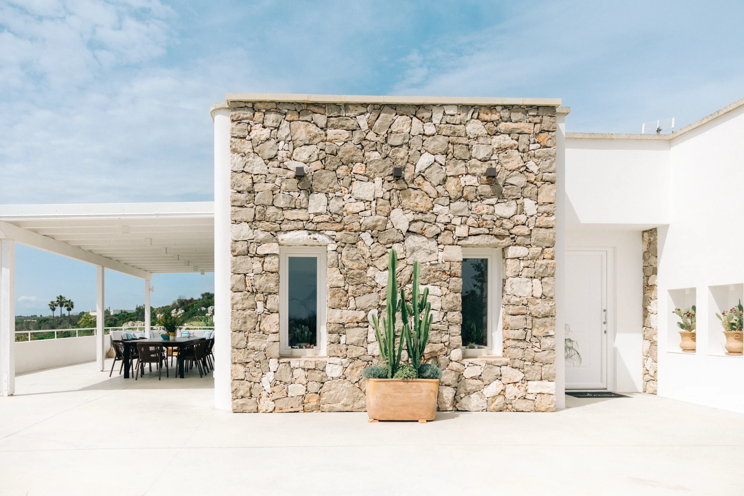 Stone facade of Villa Leucade with Mediterranean plants and minimalist outdoor lighting in Puglia.