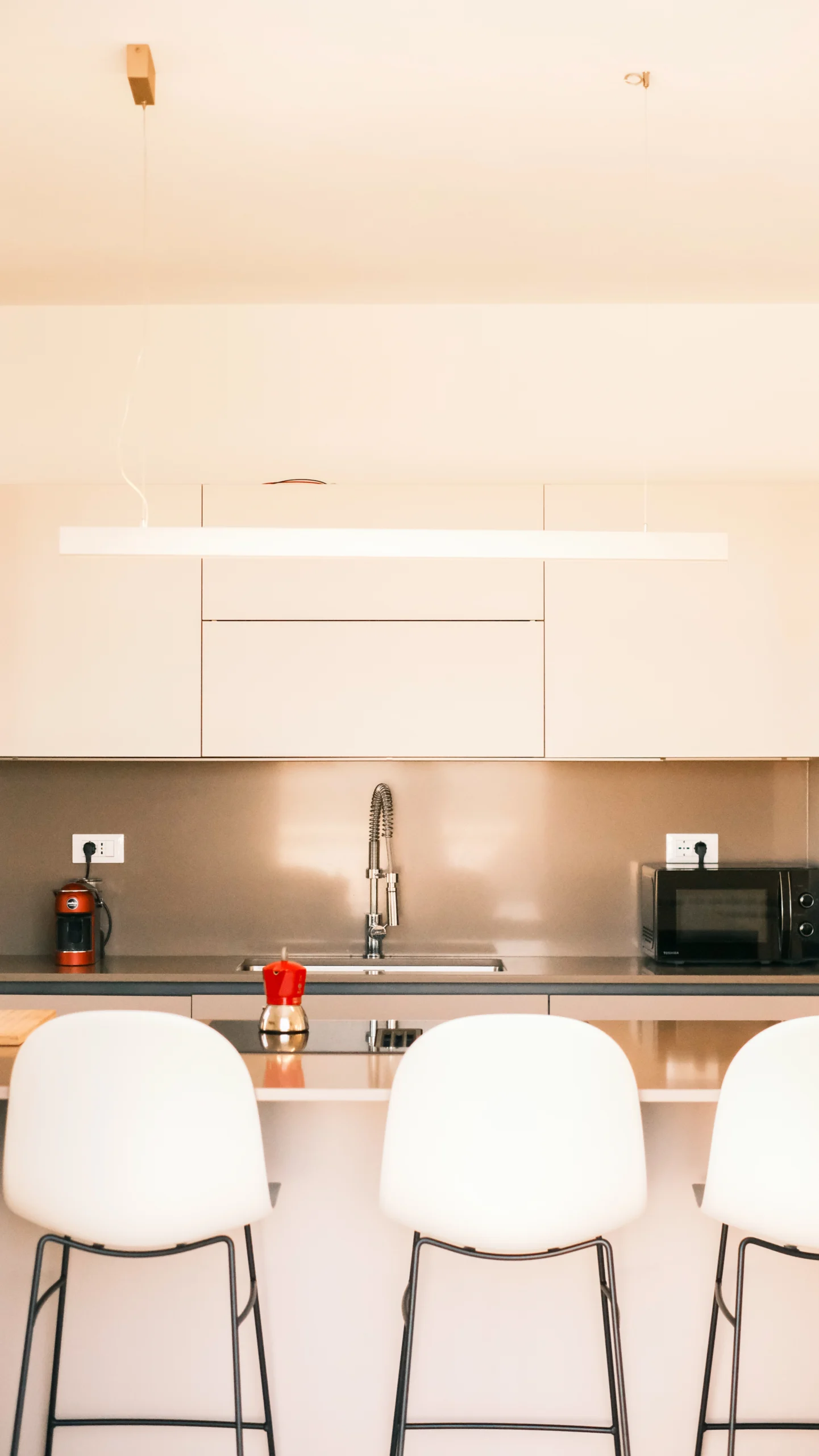 Luxury open-plan kitchen at Villa Leucade with central island, bar stools and modern Italian design.