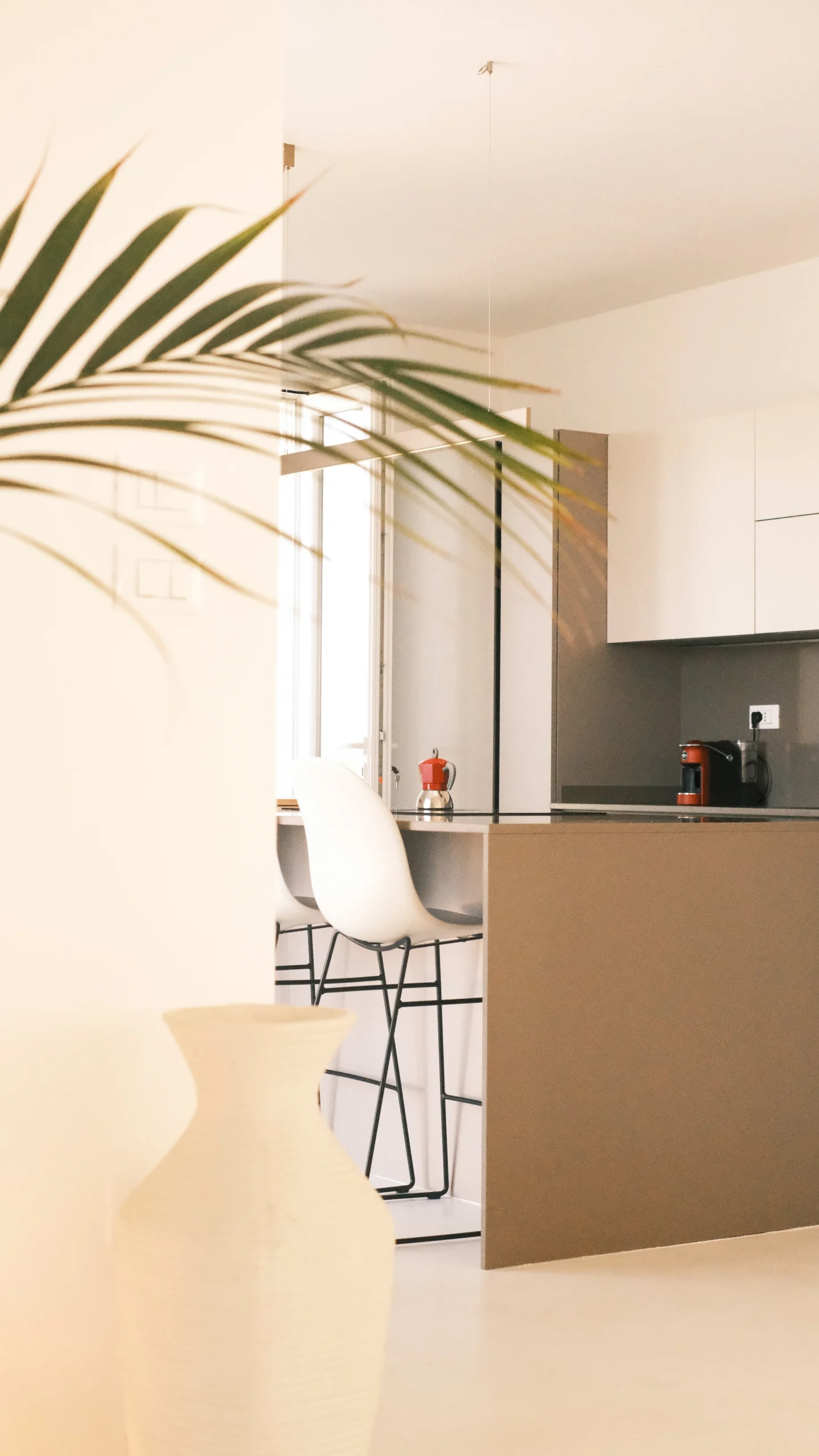 Modern kitchen interior at Villa Leucade with dining area, white walls and stone exterior visible through windows.