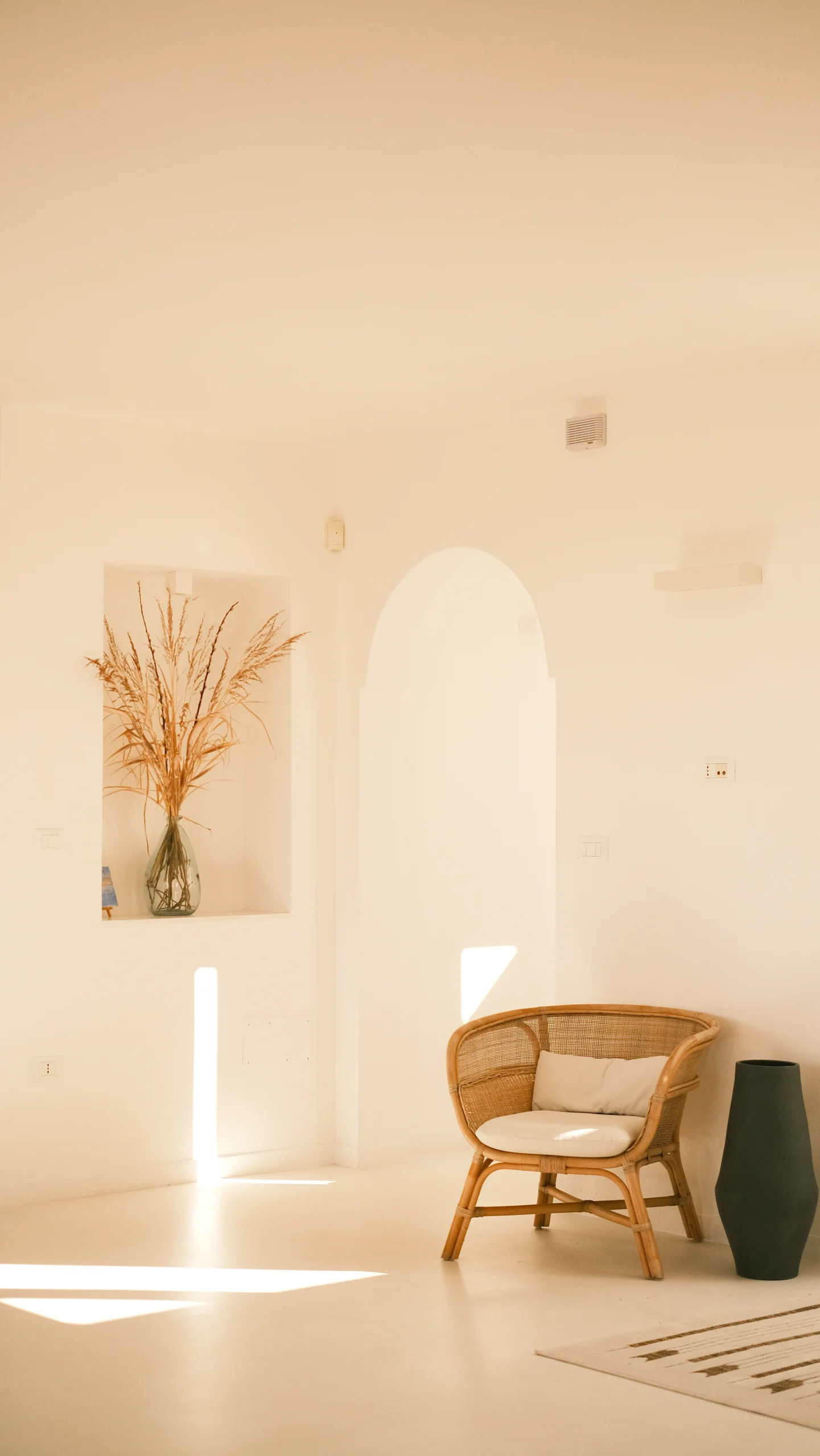 Minimalist living room at Villa Leucade with rattan armchair, natural light and Mediterranean decor style.