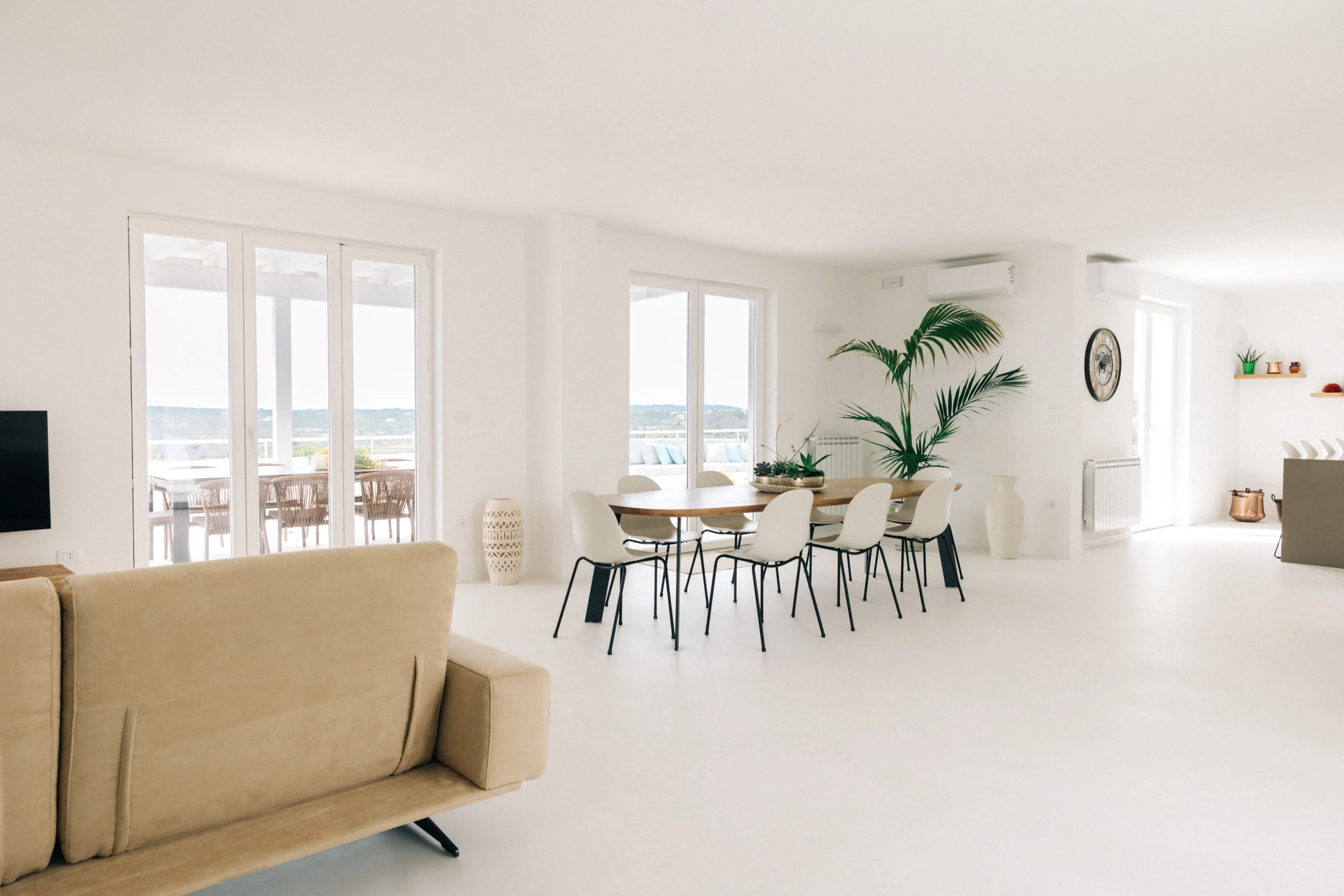 Spacious open-plan living and dining area with large terrace windows and minimalist design in luxury countryside villa Puglia
