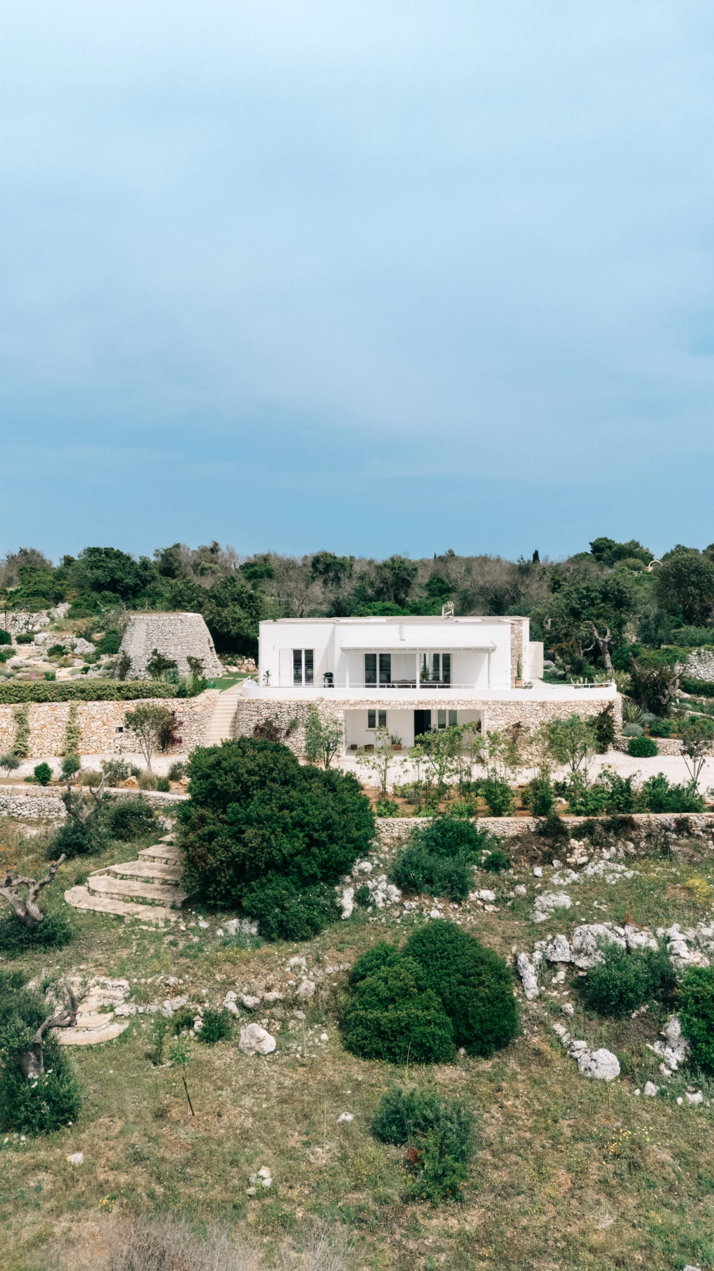 Drone view of contemporary white villa with terraced gardens and private pool in the Puglia countryside