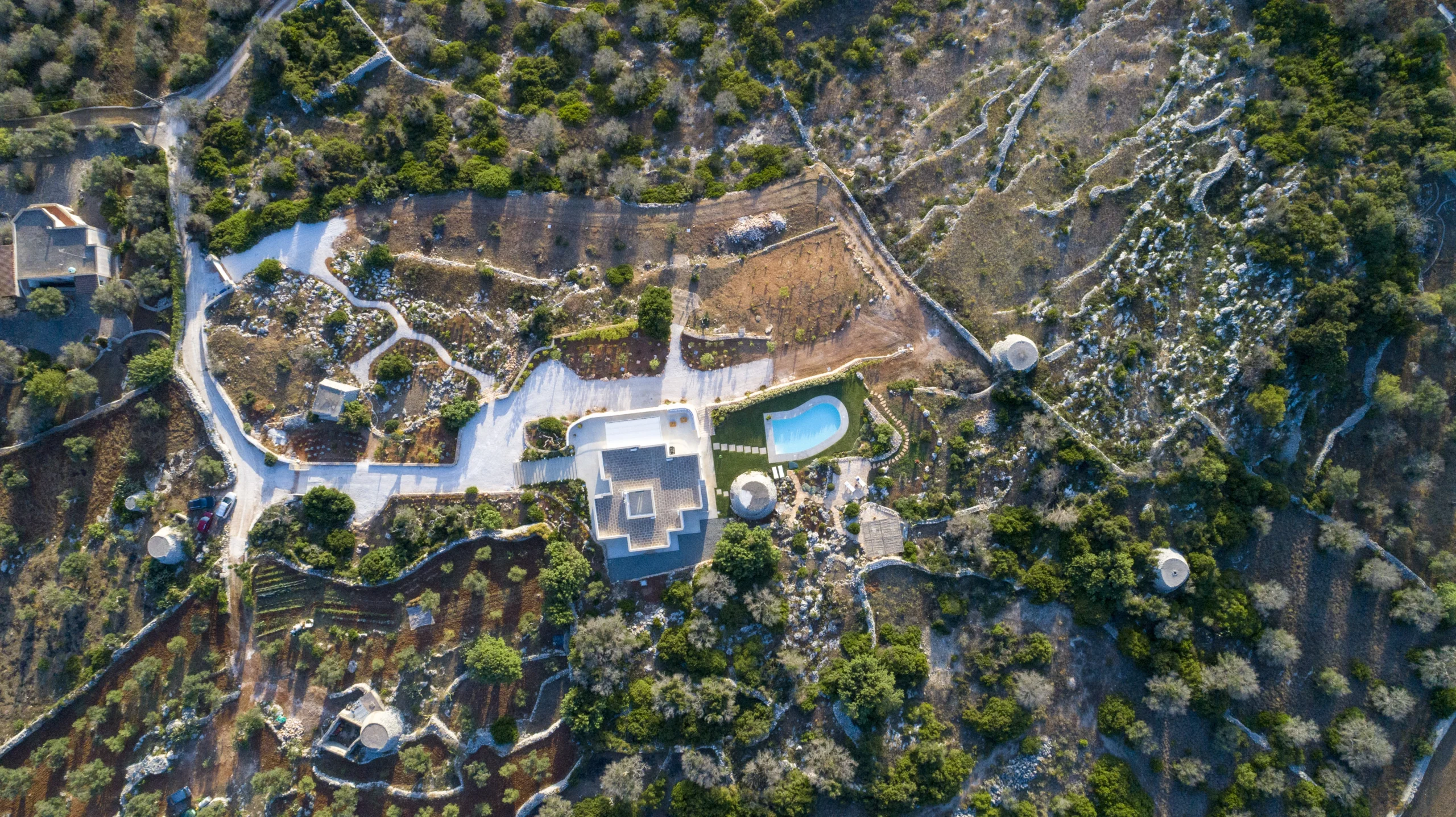 Top-down aerial view of luxury villa estate with swimming pool, trullo and Mediterranean gardens in Puglia