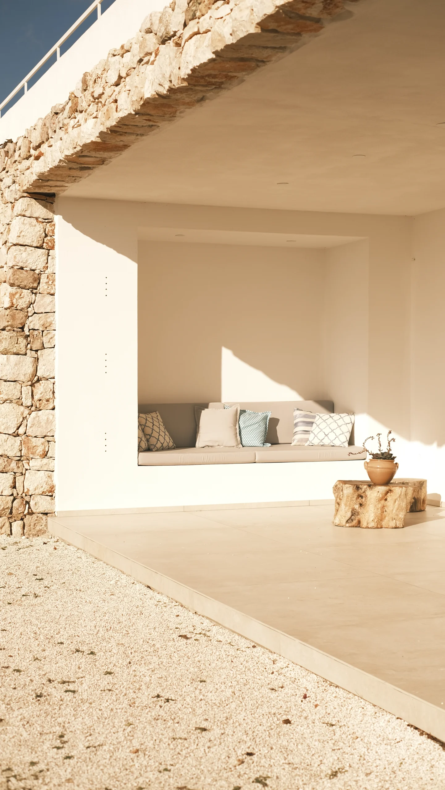 Shaded outdoor lounge with built-in sofa and stone walls on private patio at luxury villa in Puglia