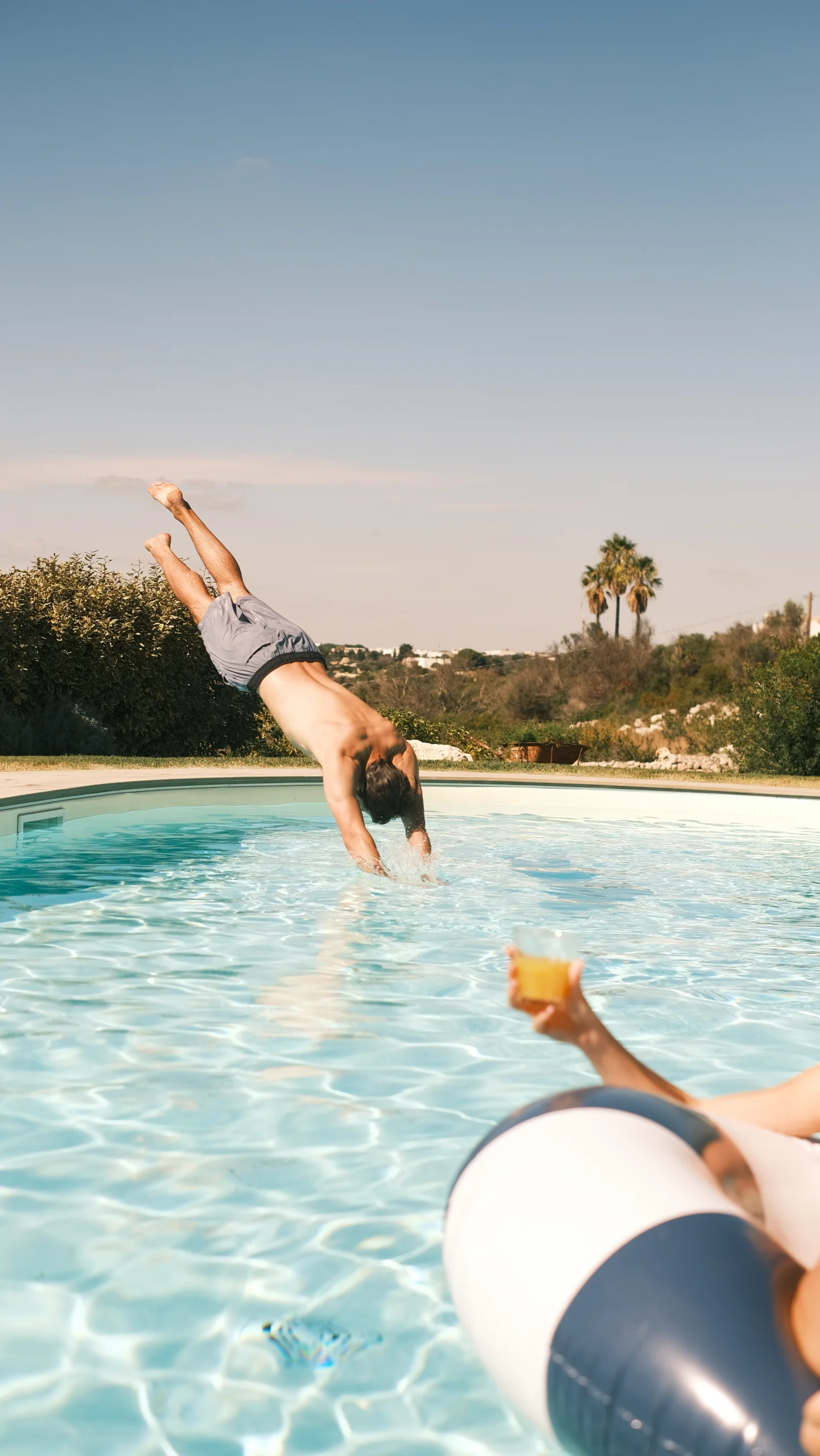 Guest diving into a private pool with Mediterranean landscape and palm trees in southern Puglia