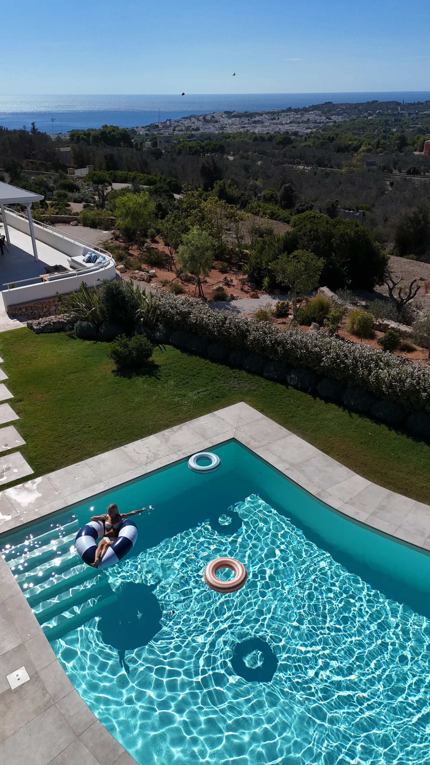 Aerial view of private pool with crystal-clear water and sea horizon in the distance, Puglia
