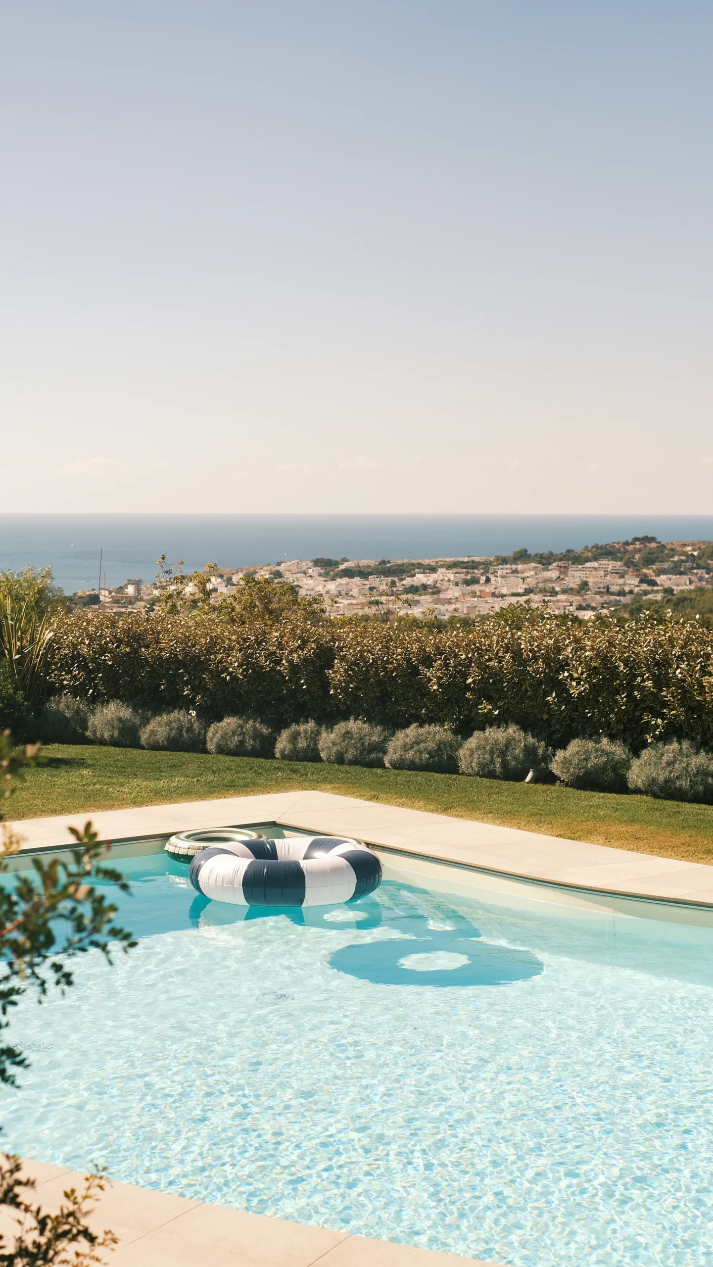 Panoramic swimming pool with inflatable float overlooking sea and village views in Puglia