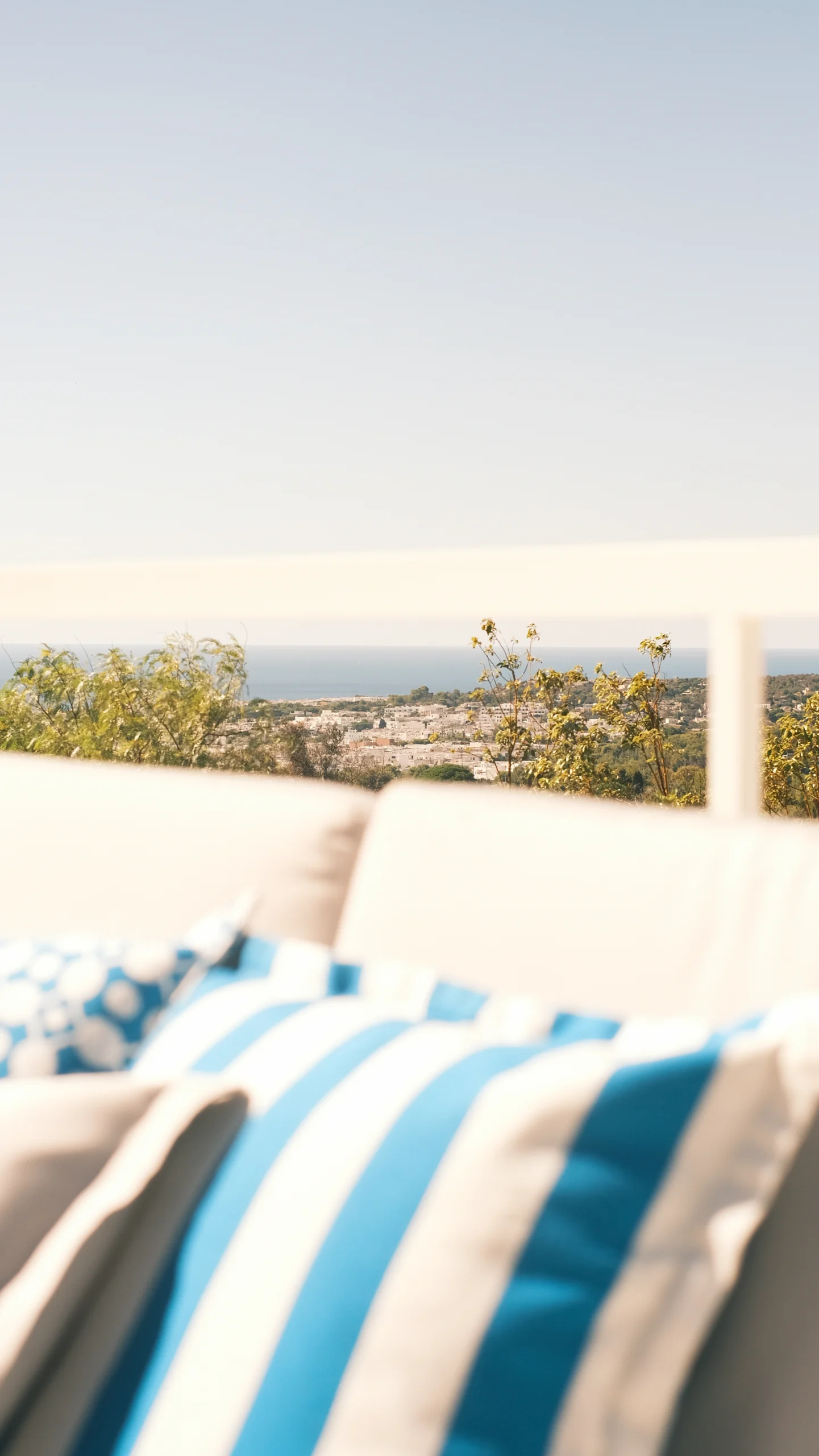 Soft-focus terrace view with striped cushions and distant sea horizon at luxury villa in Puglia