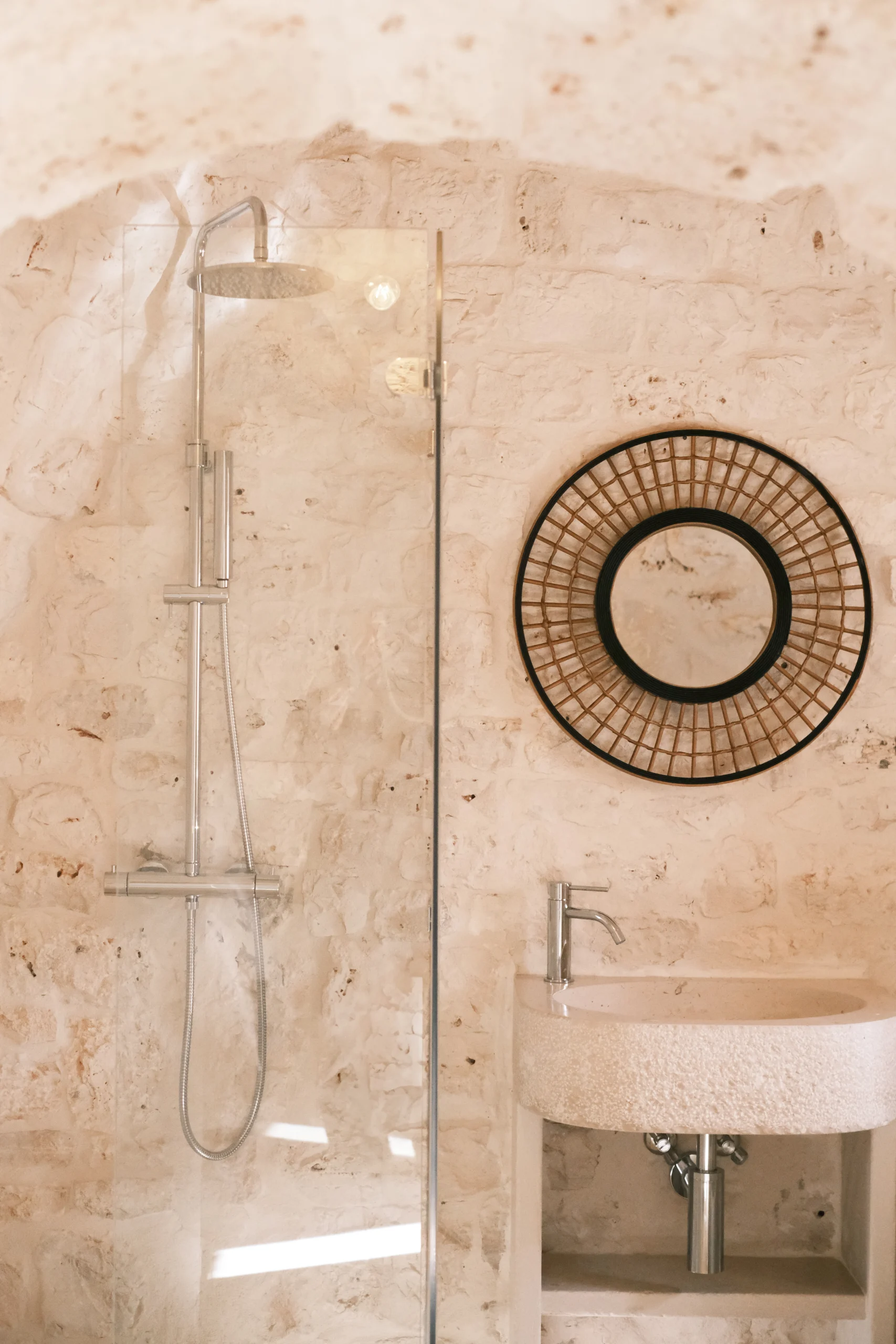 Walk-in shower with rainfall showerhead and stone sink in a vaulted stone bathroom at Villa Mira in Puglia