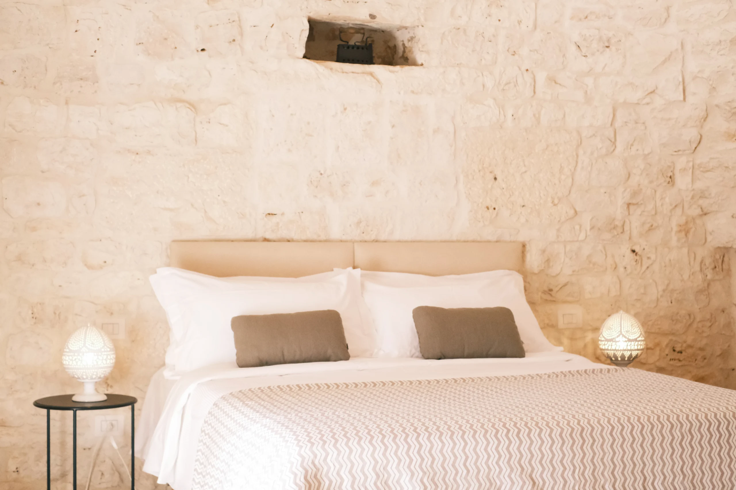 Elegant stone bedroom with king-size bed and soft lighting in a luxury villa in Puglia