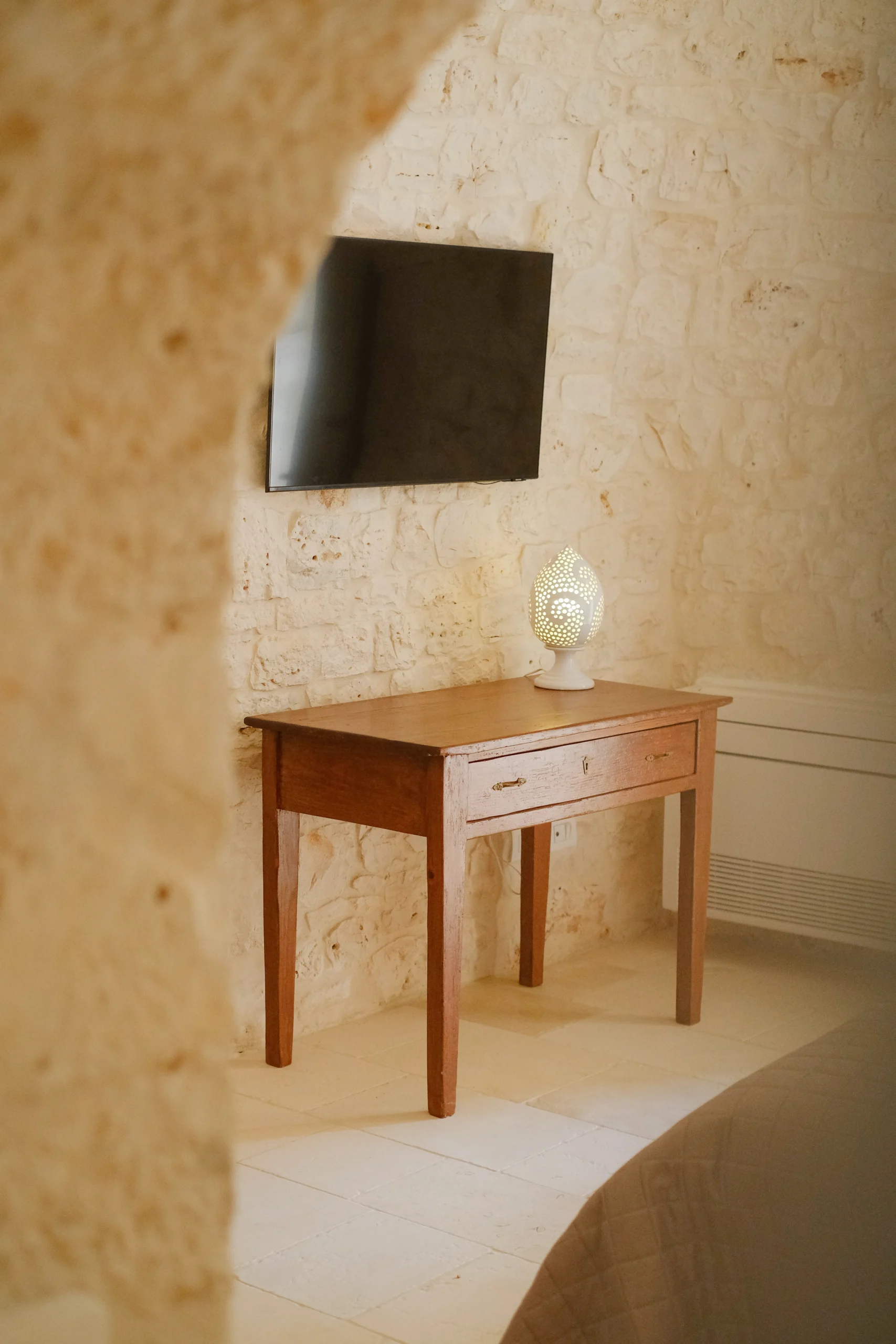 Cozy stone bedroom with designer bedside lamp and vaulted ceiling in Villa Mira, Puglia