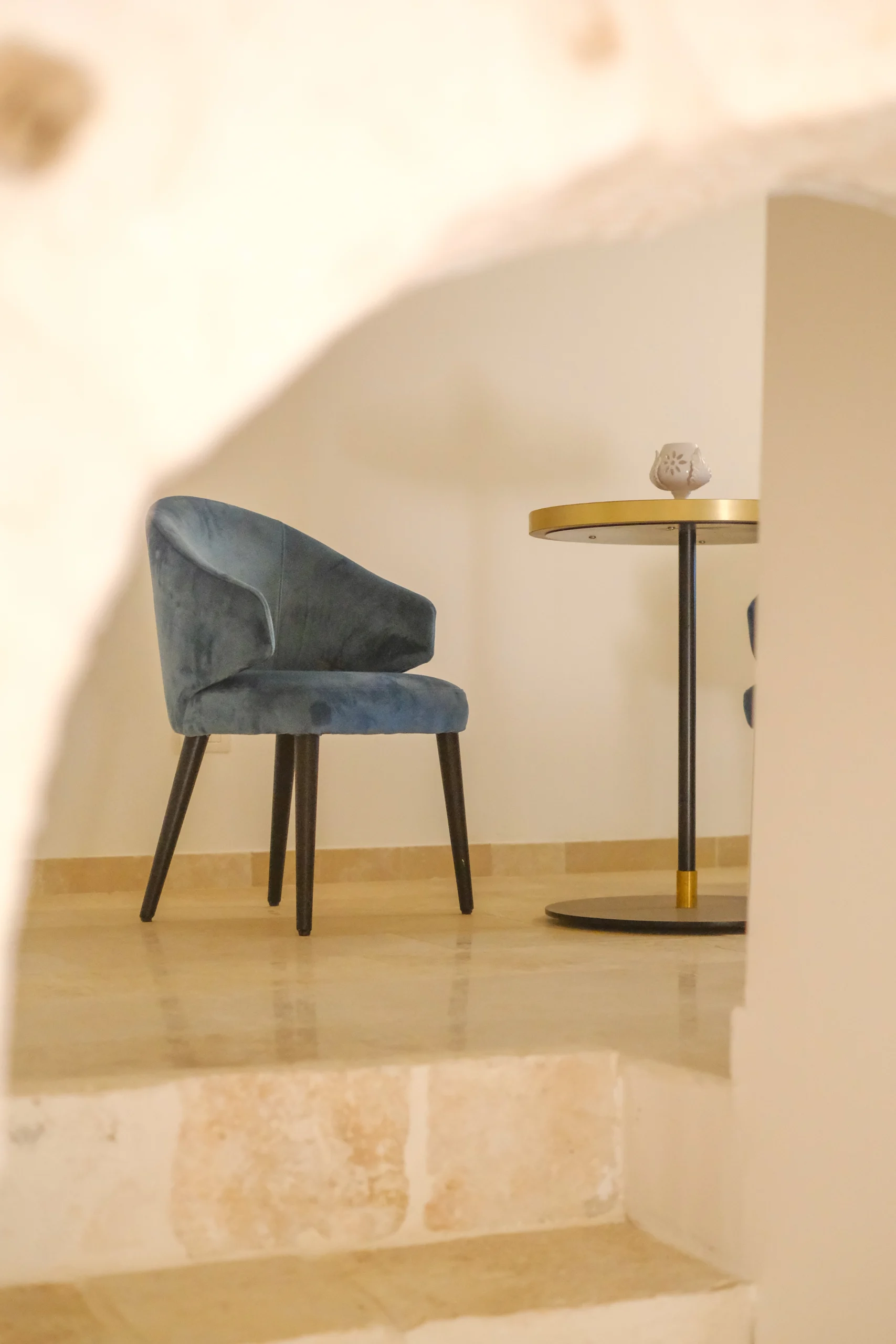 Private sitting area with velvet chair and side table inside a stone villa in Puglia