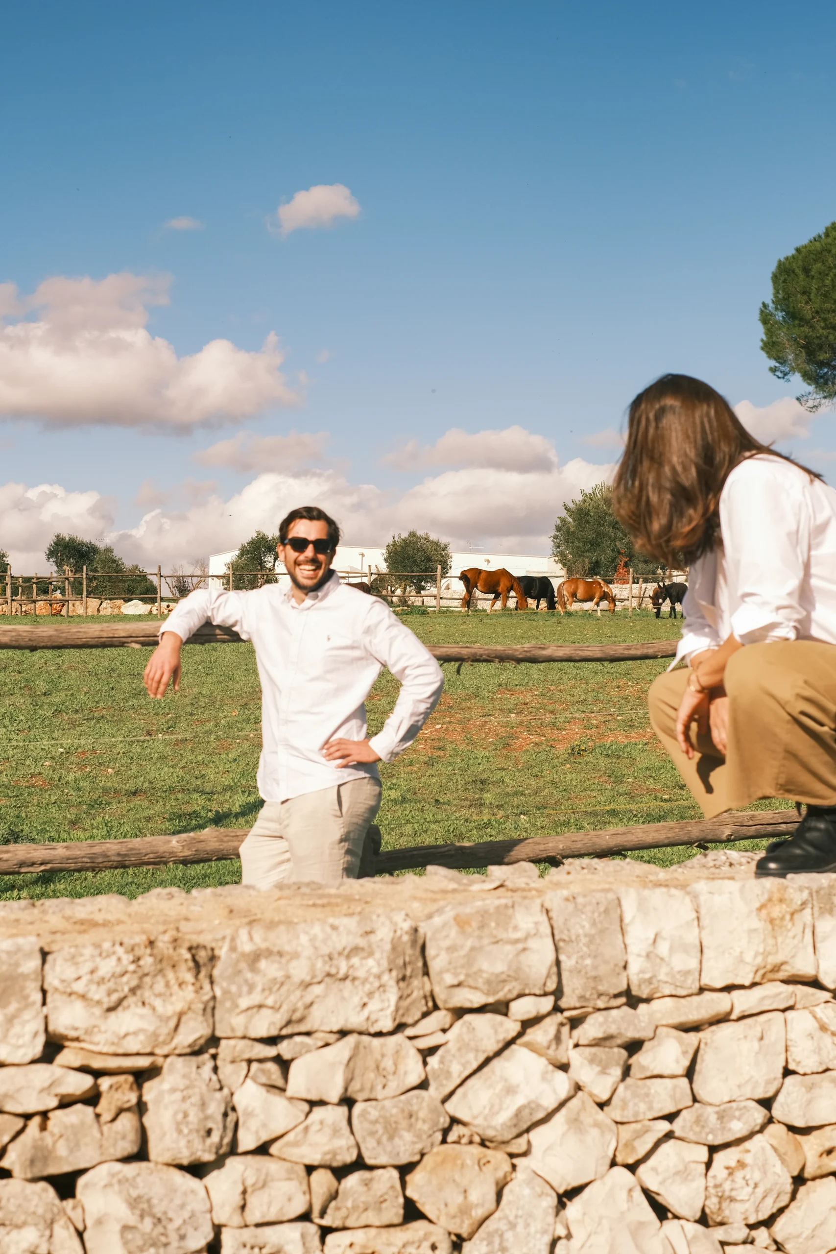 Couple enjoying the countryside near a luxury villa in Puglia, with stone walls, grazing horses and open landscapes