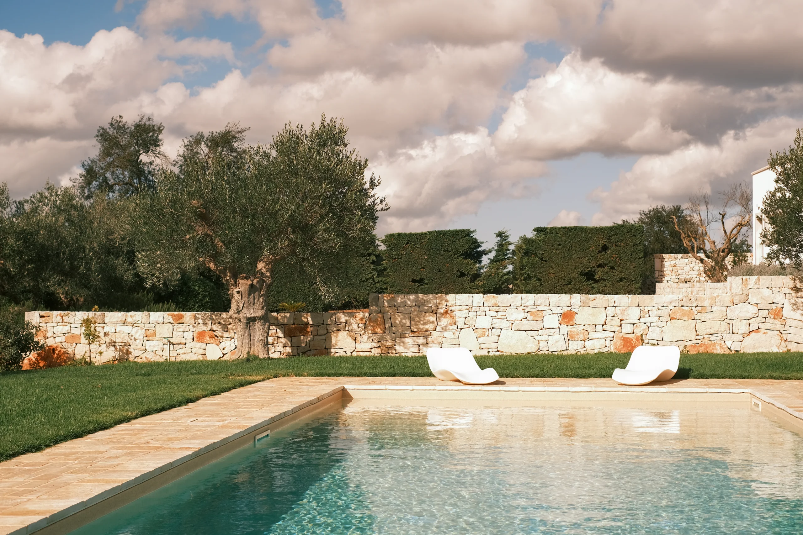Luxury swimming pool surrounded by olive trees and stone walls in a private villa in Puglia, Italy