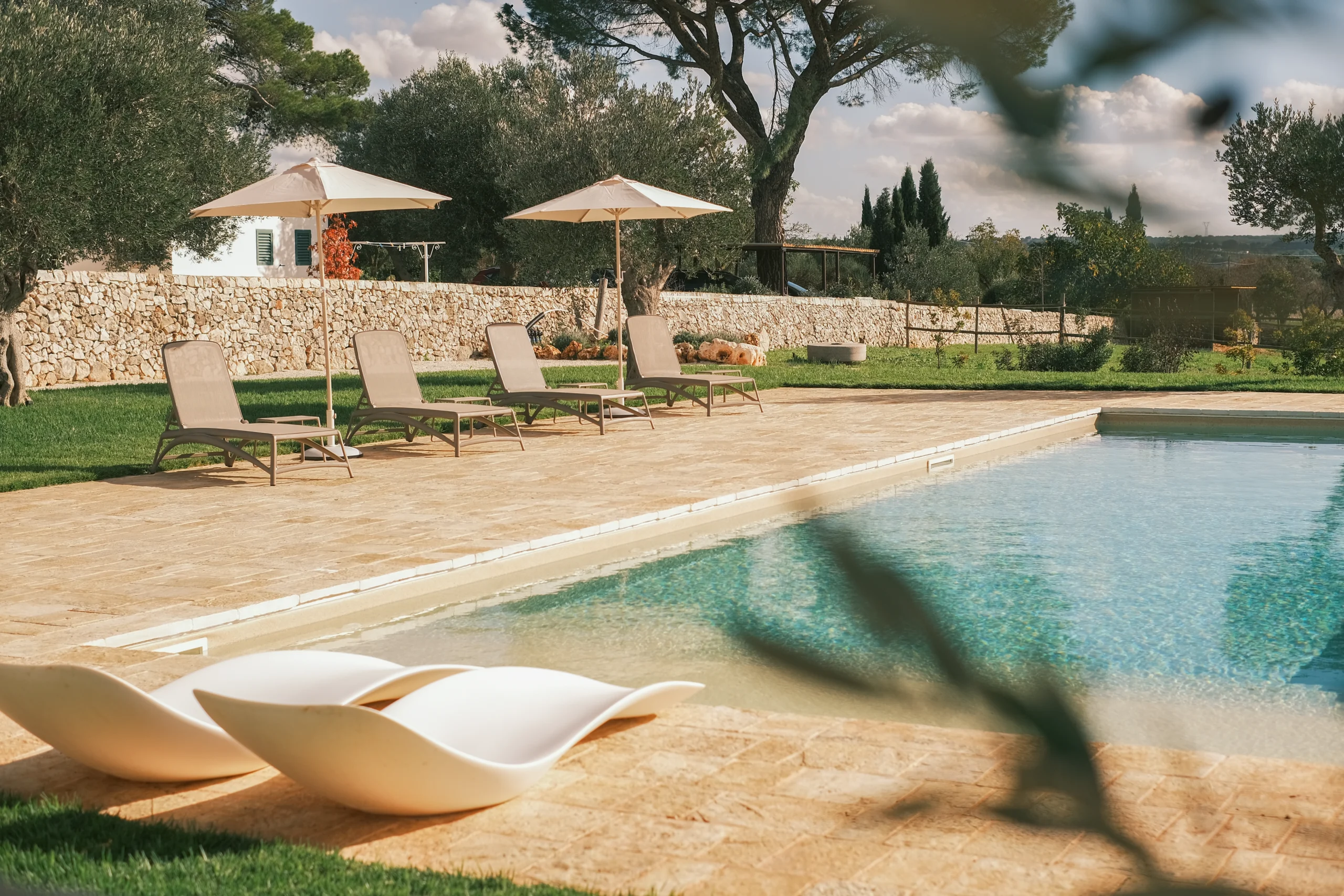 Private villa pool with sun loungers and parasols overlooking the Puglian countryside