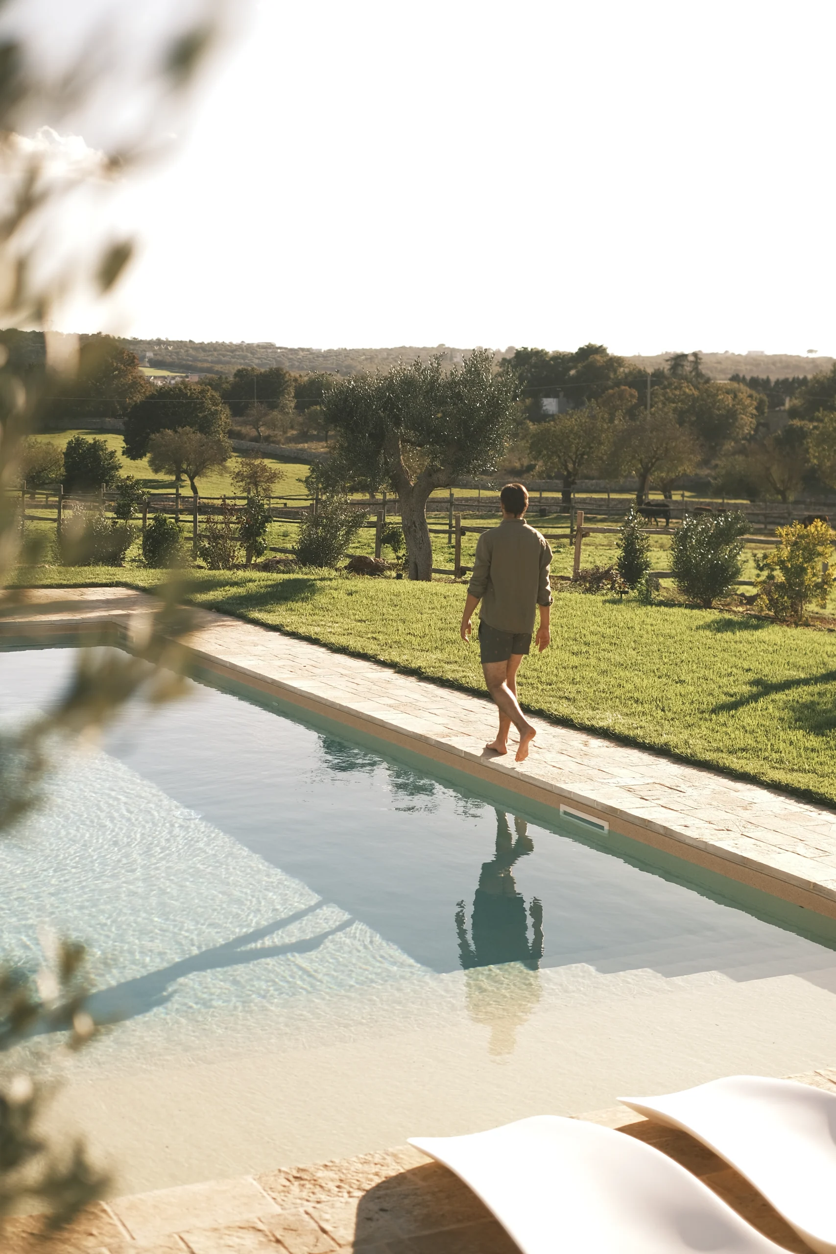 Guest walking barefoot by a private swimming pool at sunset in a luxury Puglia villa