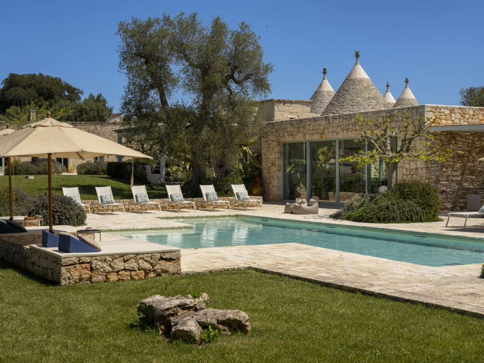 Luxury stone villa with traditional trulli cones, large swimming pool, sun loungers and ancient olive trees in the Puglia countryside